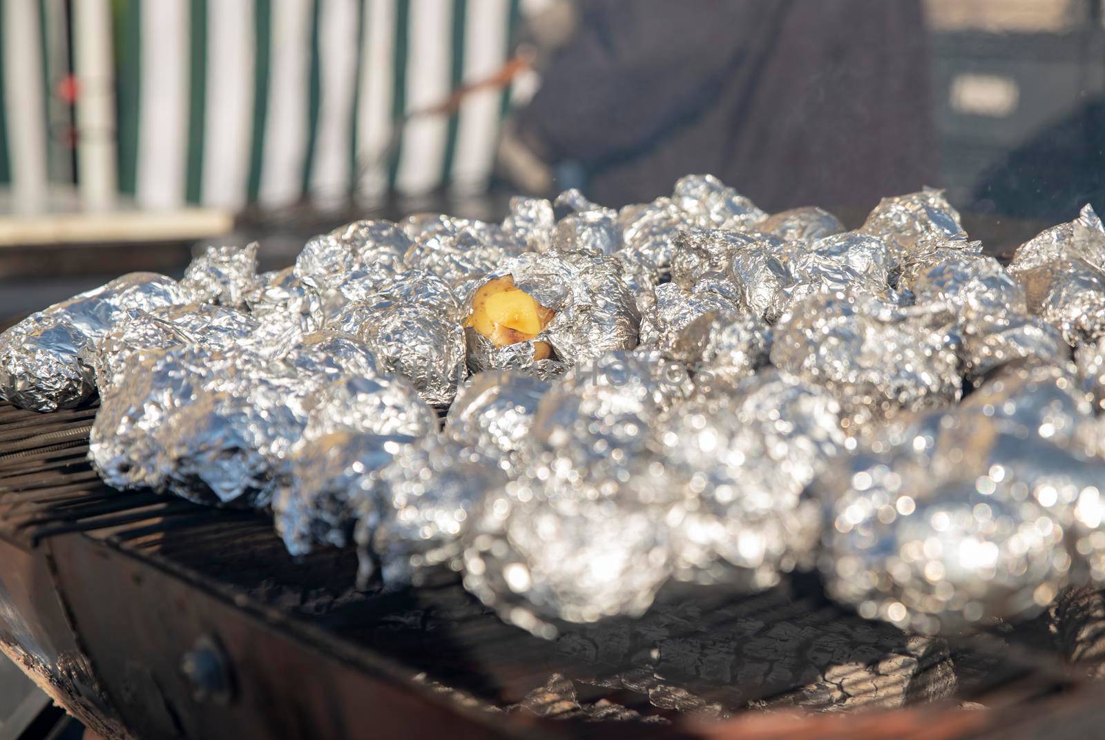Many potatoes in foil on the barbecue