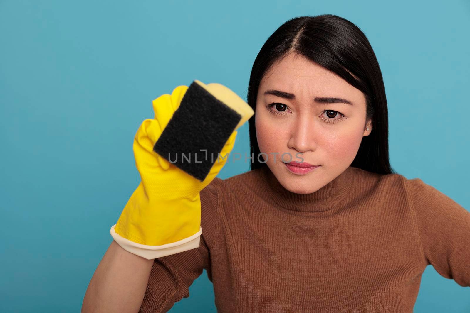 Serious confidence asian young housewife wearing yellow gloves holding a sponge, Housewife worker, Cleaning home concept, Faithful tired and overwhelmed housework housewife from day to day chores
