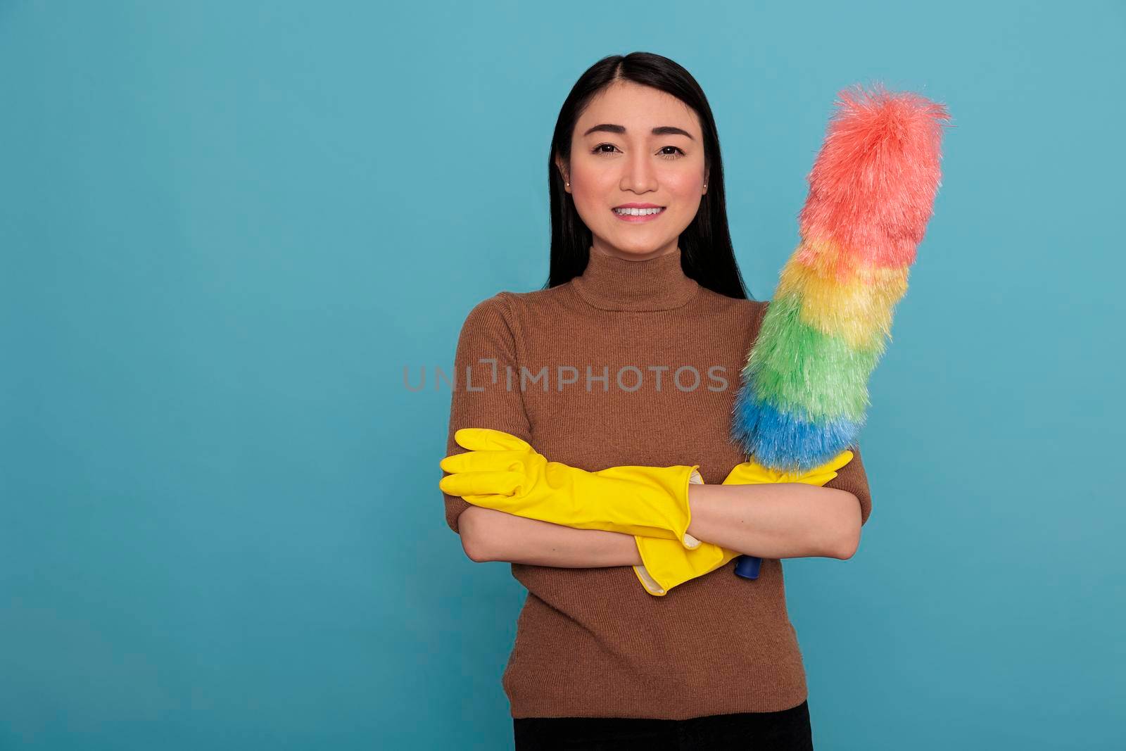 Satisfied cheerful and optimistic asian housemaid cross hands holding colorful dust brush in yellow glove, Housewife worker, Cleaning home concept, Feeling joyful and positive at work