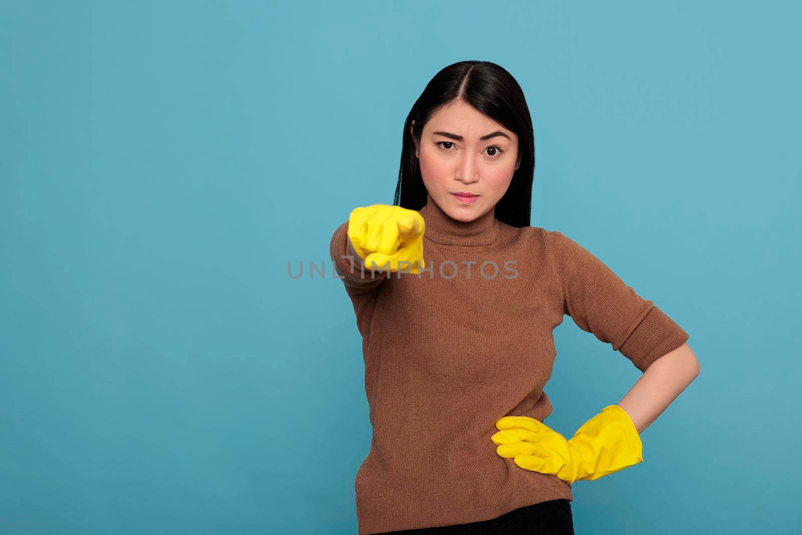 Angry sad and exhausted asian housemaid at work wearing yellow gloves pointing finger to the front, Cleaning home concept, Stressed unhappy woman with negative state of mind