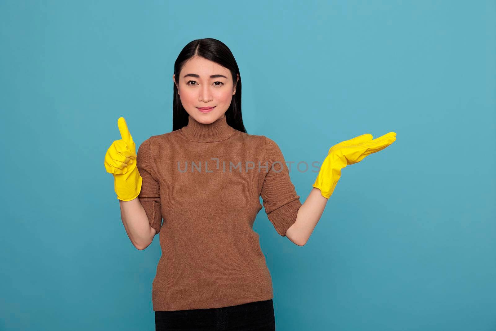 smiling happy cheerful asian young woman from chores pointing hand aside at copy space and wearing yellow glove, Cleaning home concept, Optimistic satisfied positive female thumbs up