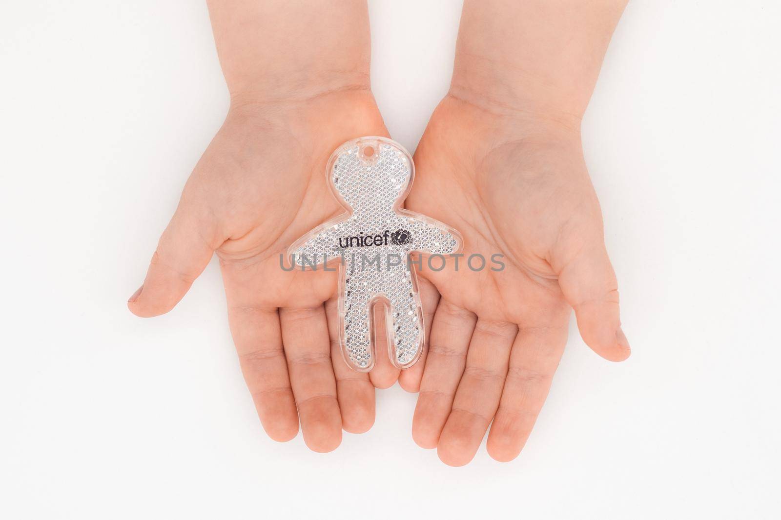 PARIS, FRANCE - MAY 17, 2020Children's hands holding a small figure with the UNICEF symbol Isolated on white background.
