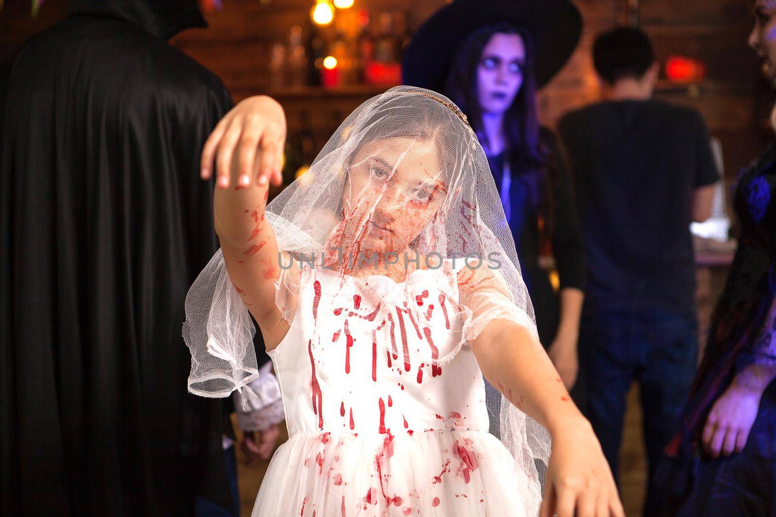 Portrait of little girl dressed up like a bride covered with blood at halloween party by DCStudio