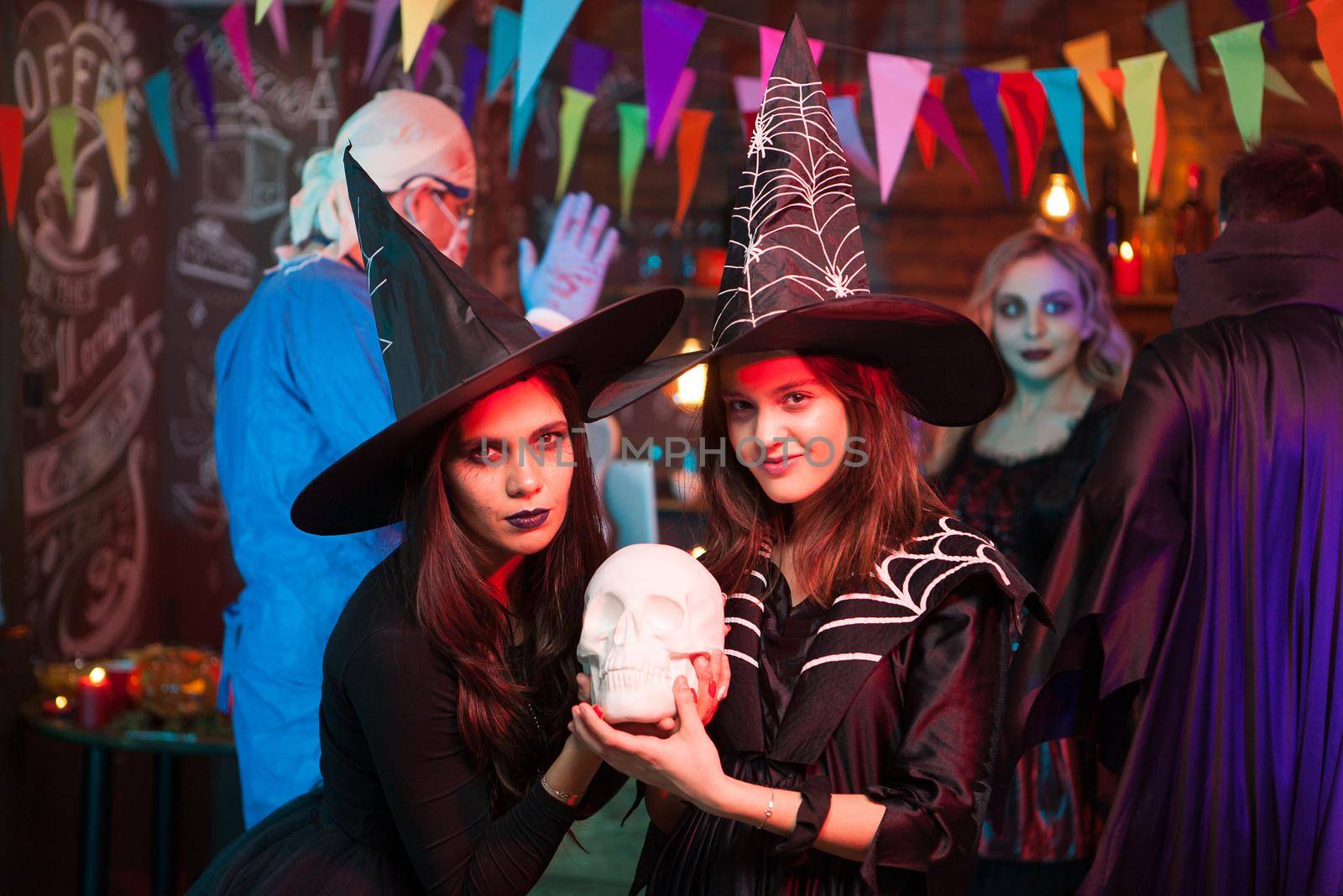 Young mother with her daughter dressed up like witches at a halloween party. Cheerful girl with big witch hats.