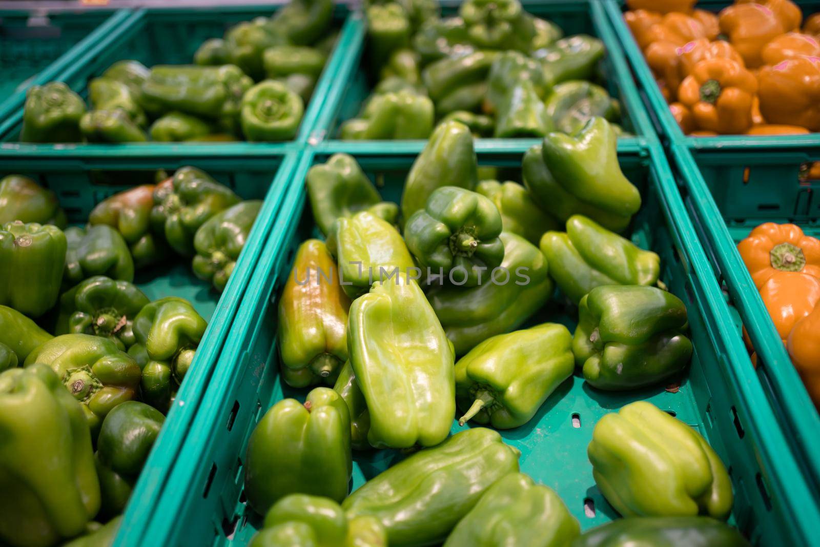 Raw juicy green bell pepper in plastic basket on the shelf in the supermarket. Sweet pepper on grocery store display