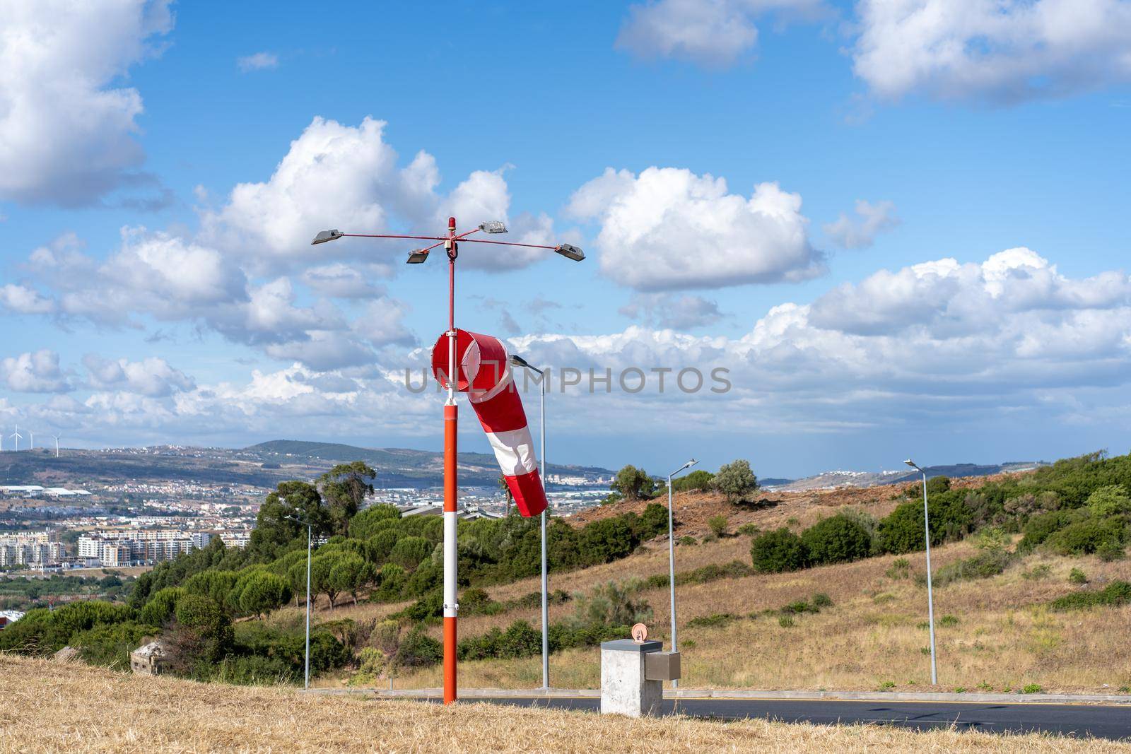 Wind sock fly. Summer hot day on private sporty airport with abandoned windsock, wind is blowing and windsock is lazy moving. Windsock with cloud sky mountain and road with cars on background