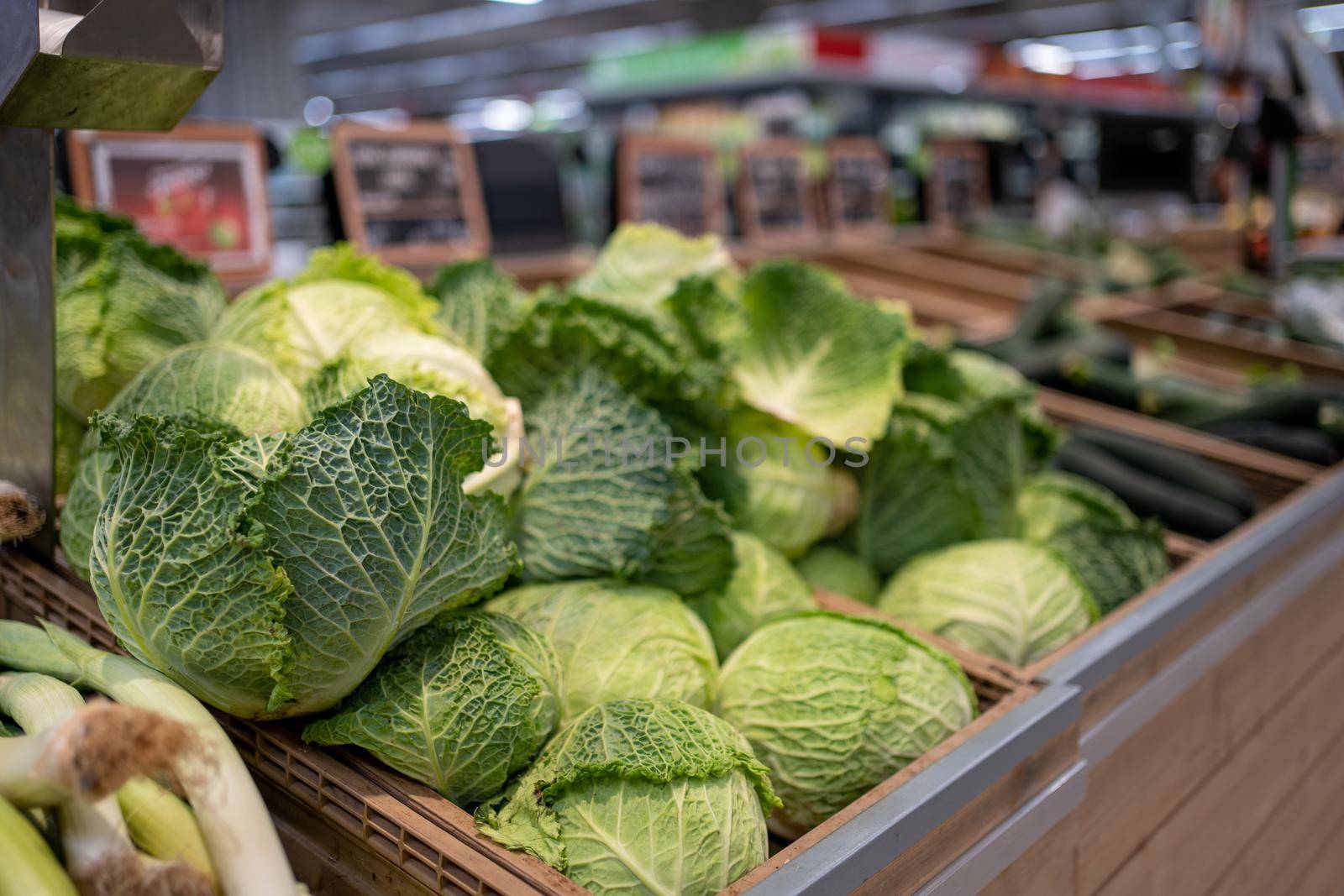 Raw juicy cabbage in plastic basket on the shelf in the supermarket. Green cabbage on grocery store display