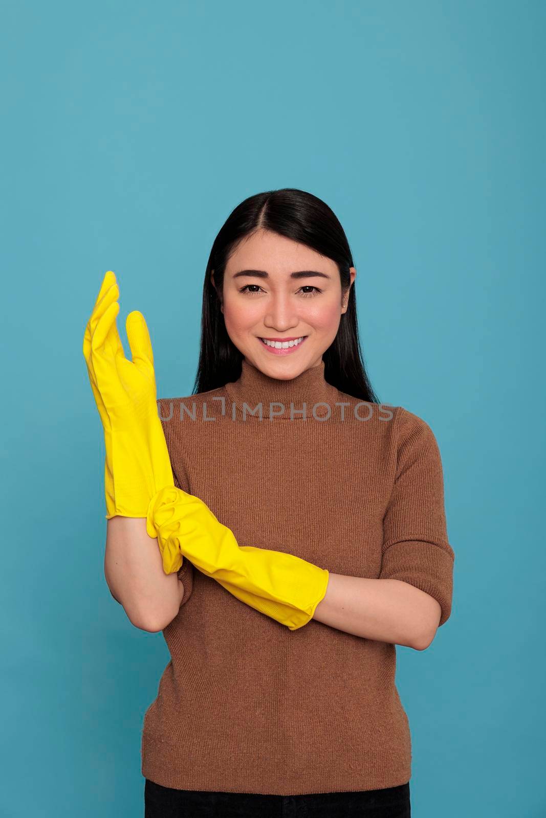 Smiling glad and delighted asian housemaid putting yellow rubber gloves on hand ready to do household duties, Cleaning home concept, Joyful optimistic female from chores positive state of mind
