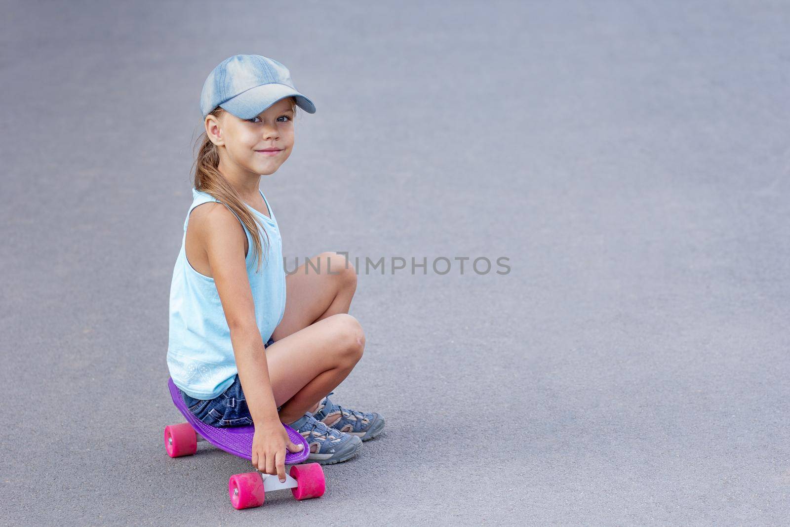 Smiling child sitting on skateboard on road by TatianaFoxy