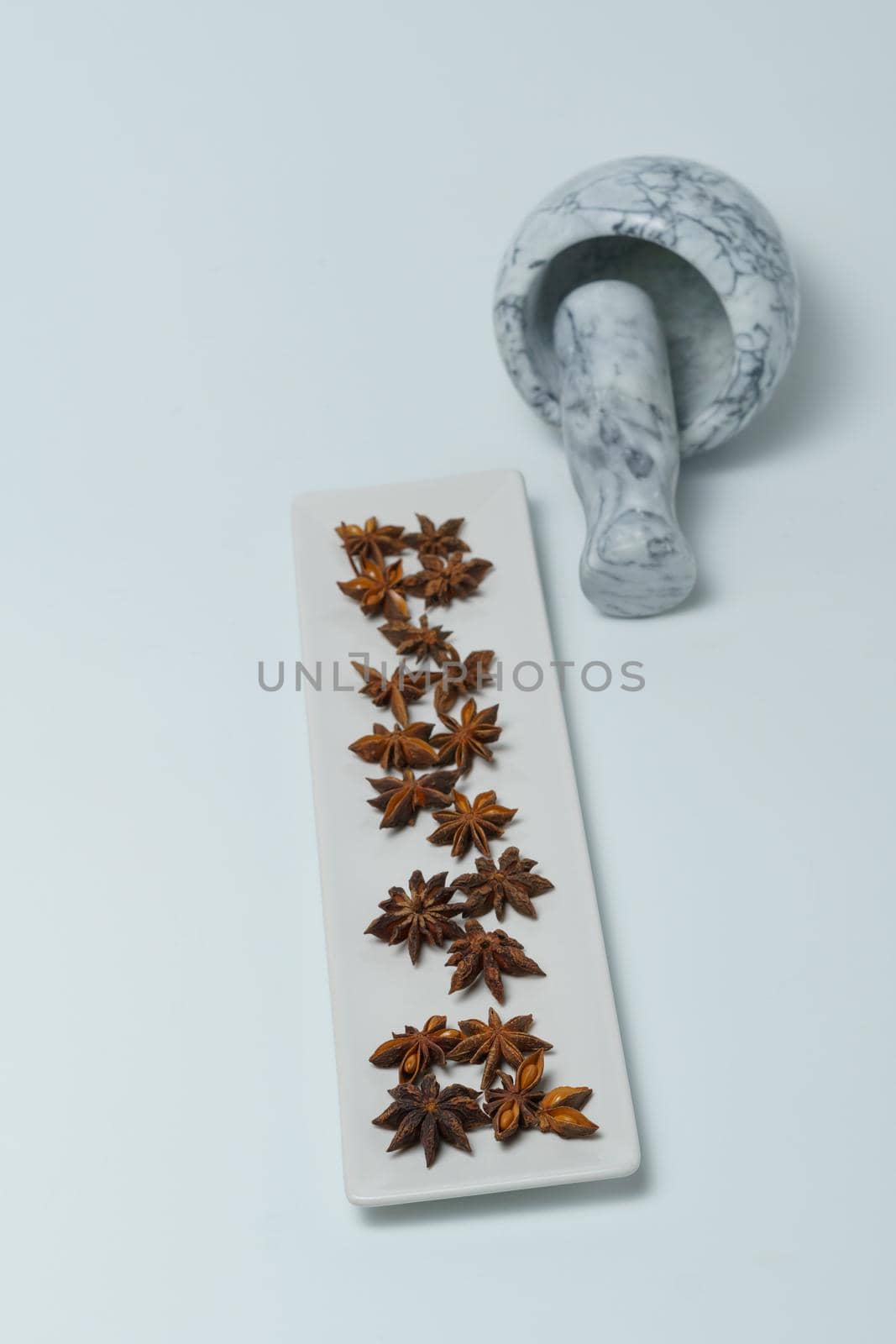 close-up of star anise illicium verum in a white dish with a marble mortar isolated on white background and copy space