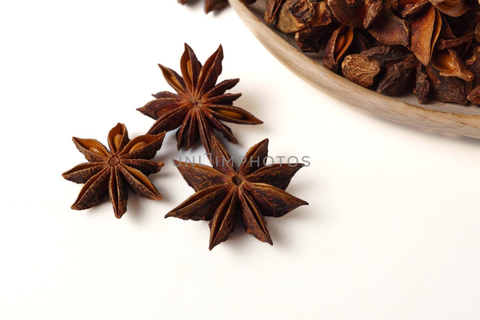 star anise illicium verum in a wooden spoon isolated on white background by joseantona