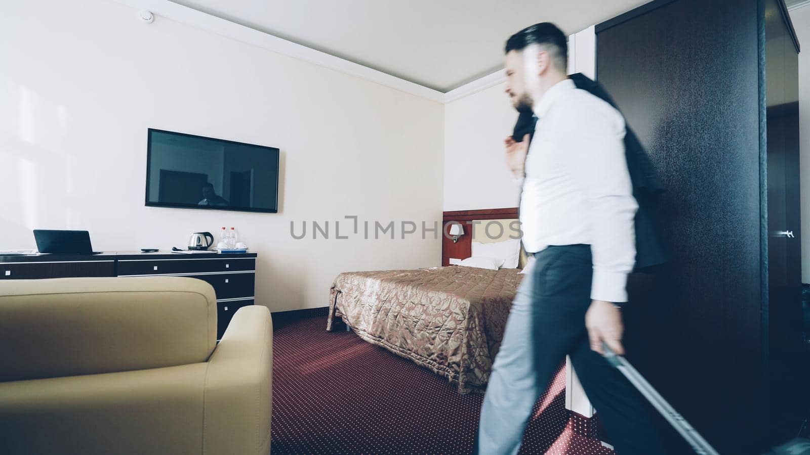 Young businessman entering hotel room after check-in. Travel, business and people concept