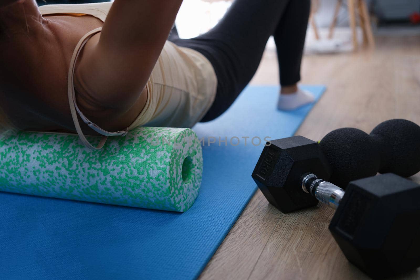 Closeup of woman riding cork massage roller to relieve tension in back muscles. Exercises for spine concept