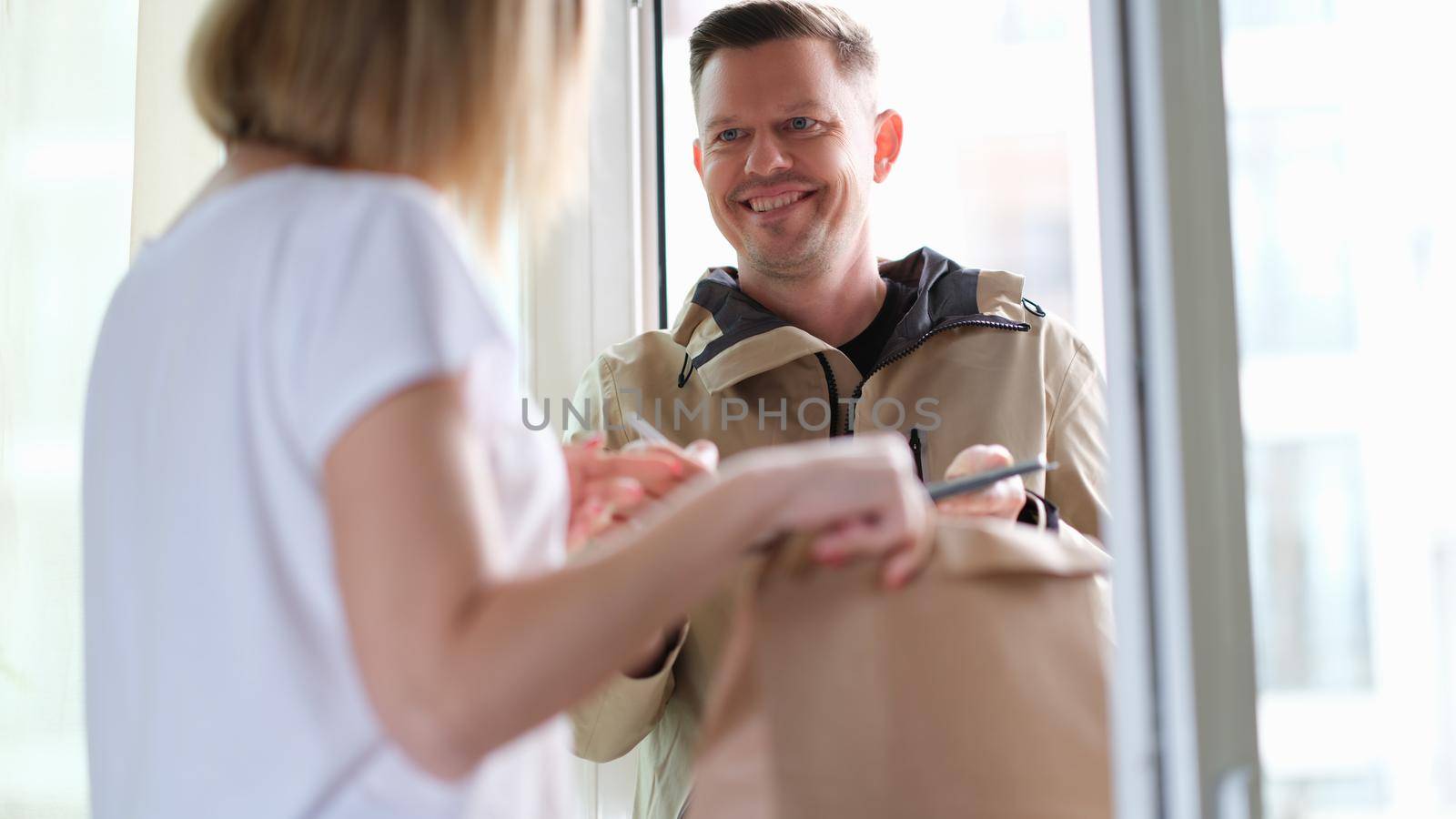 Smiling courier man delivers parcel to woman. Home delivery service concept