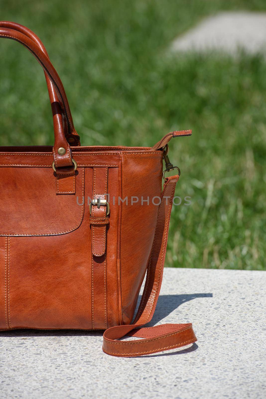 close-up part photo of luxury orange leather bag on a white marble. outdoors photo