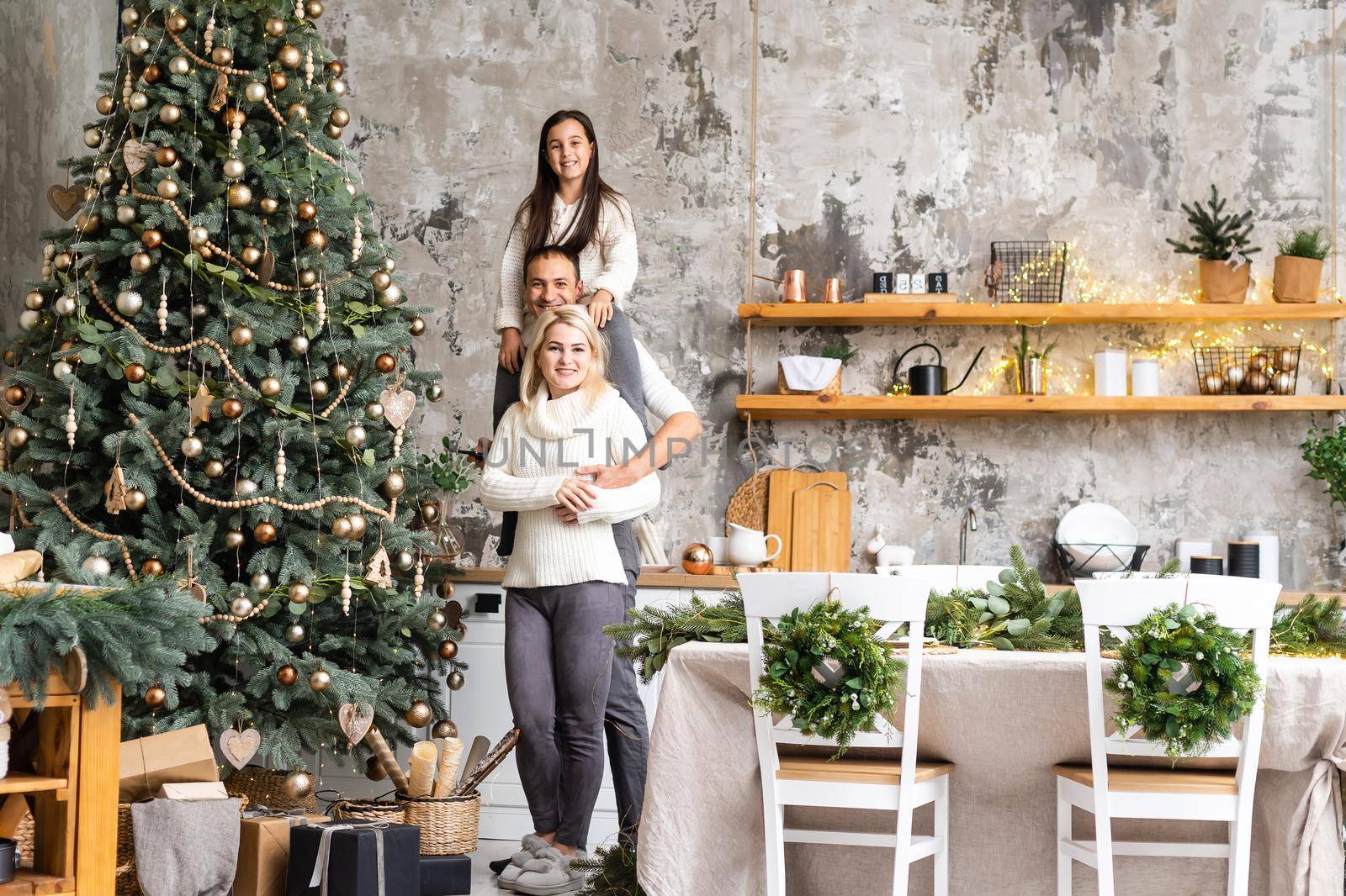 Merry Christmas and happy Holidays. Mom, dad and daughter decorating christmas tree