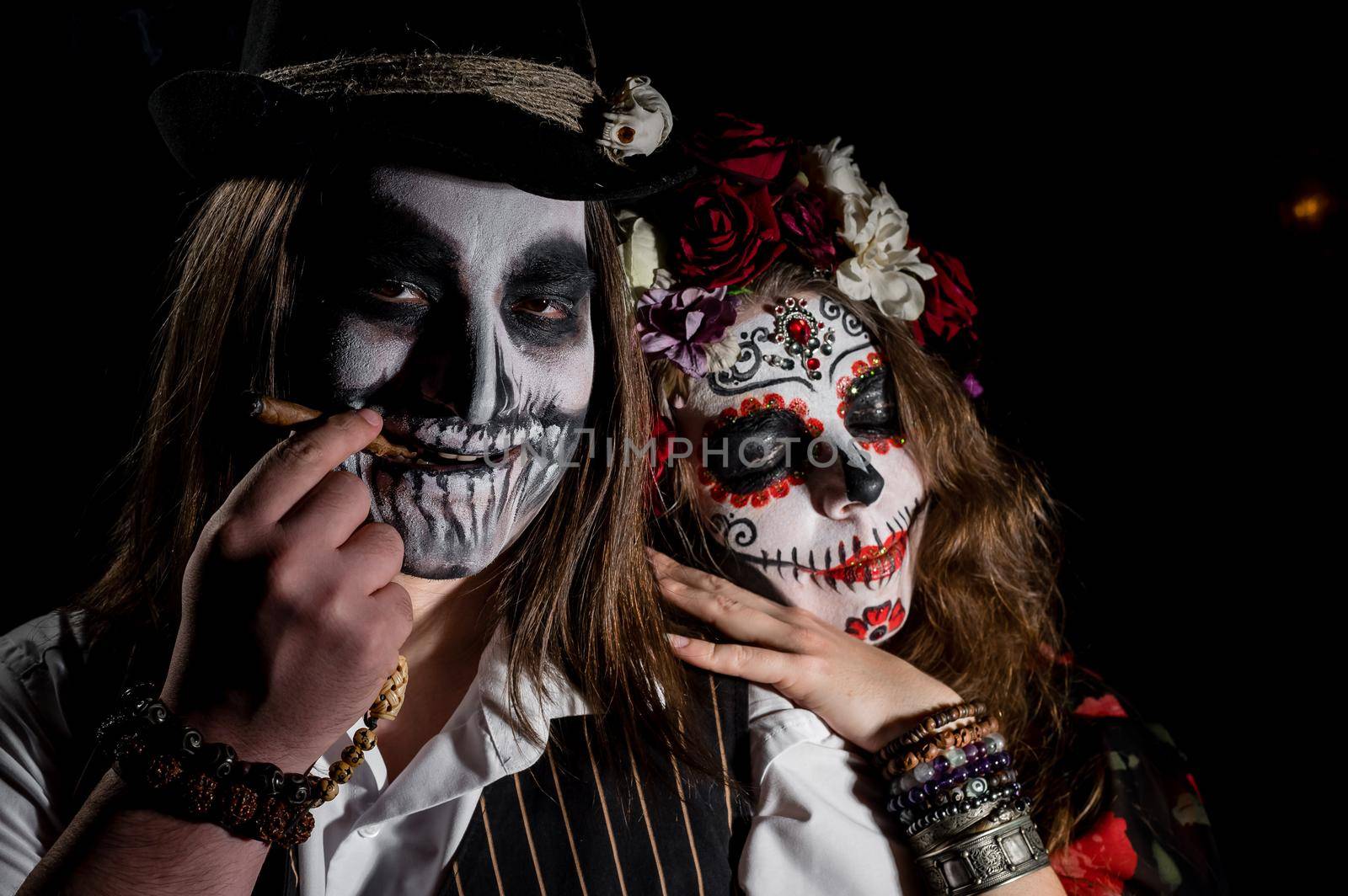 Woman in santa muerte costume and man in skeleton bodypainting for halloween