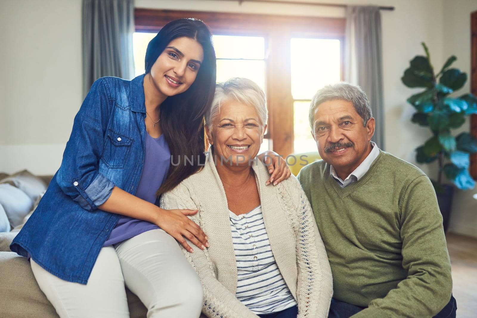 We have all the love and support we need. Portrait of a beautiful senior couple posing with their daughter while sitting on a sofa together at home. by YuriArcurs