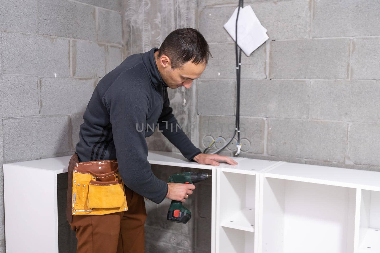 Young man assembling furniture in new house