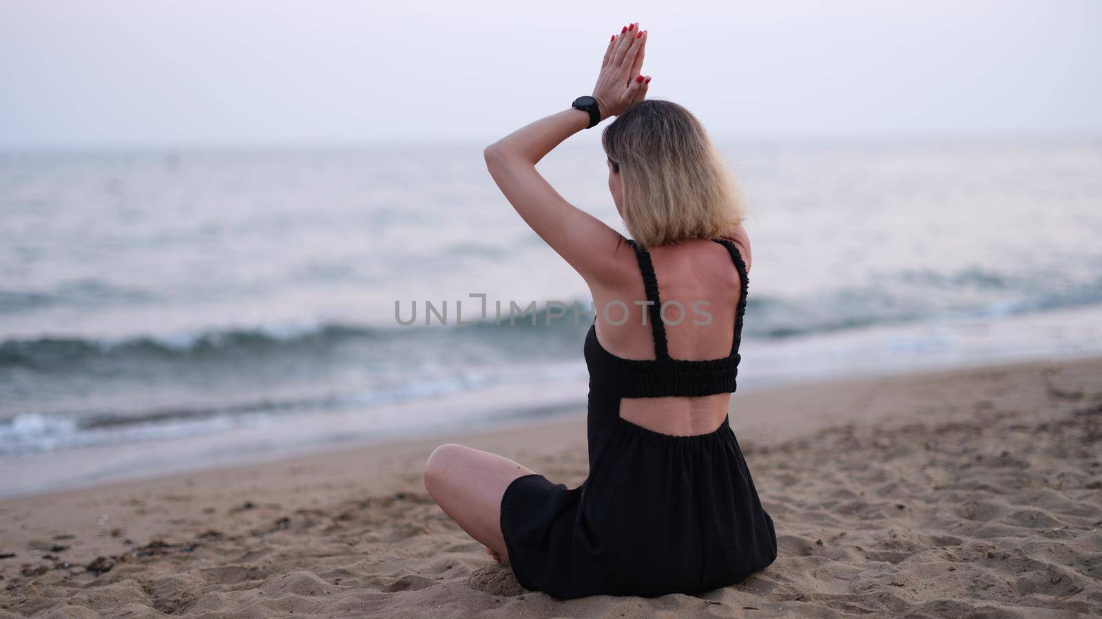 Meditating yoga woman sits on seaside beach. Relaxing meditation on beach concept