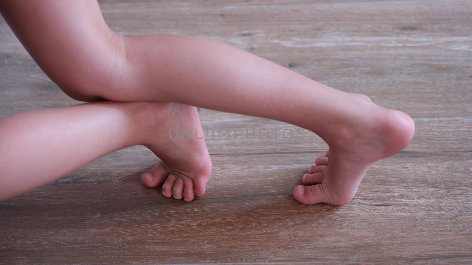 Children feet slide on wooden laminate at home. Floor covering for kids concept