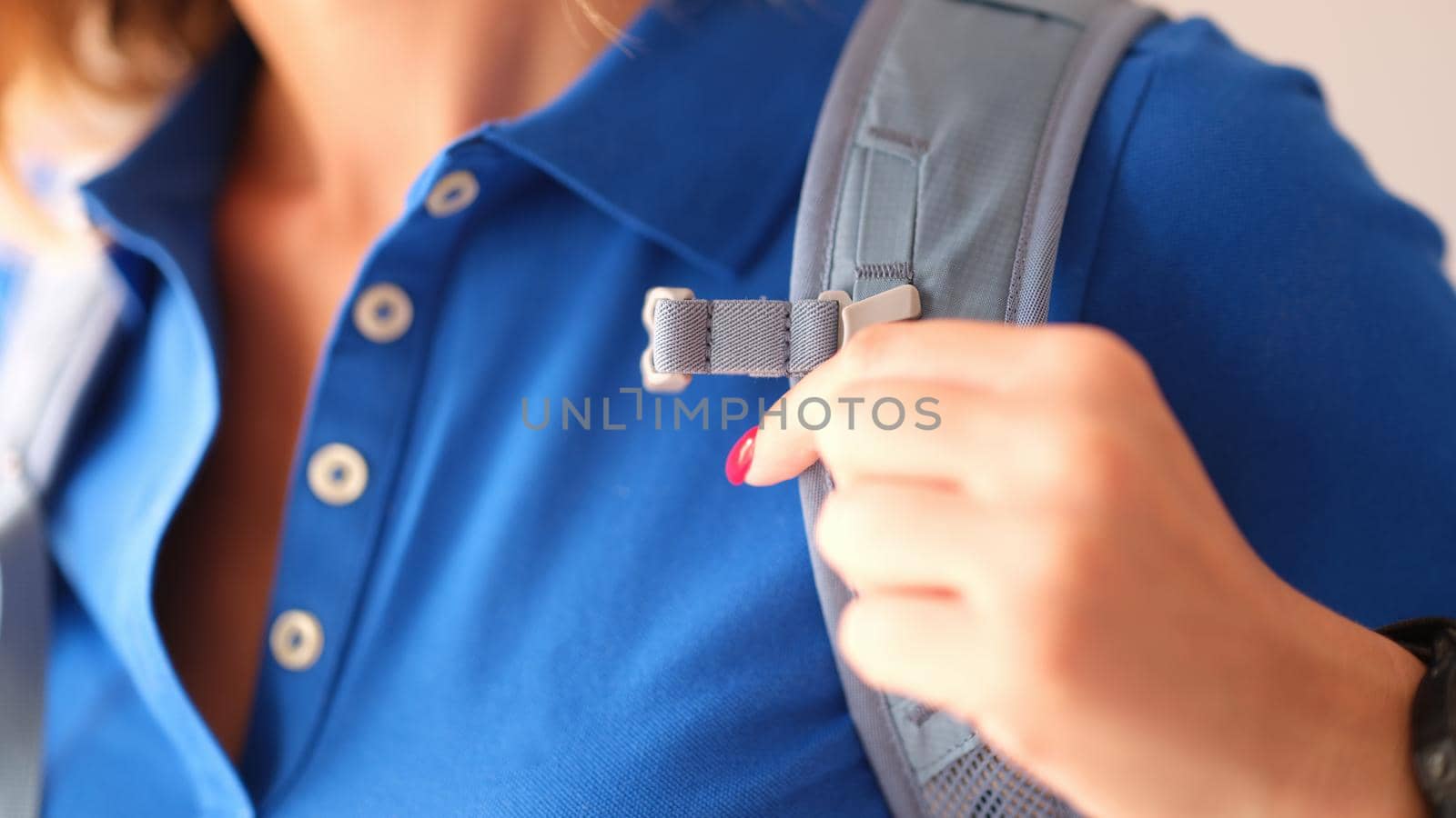 Closeup of woman in blue polo and gray harness of sports backpack by kuprevich