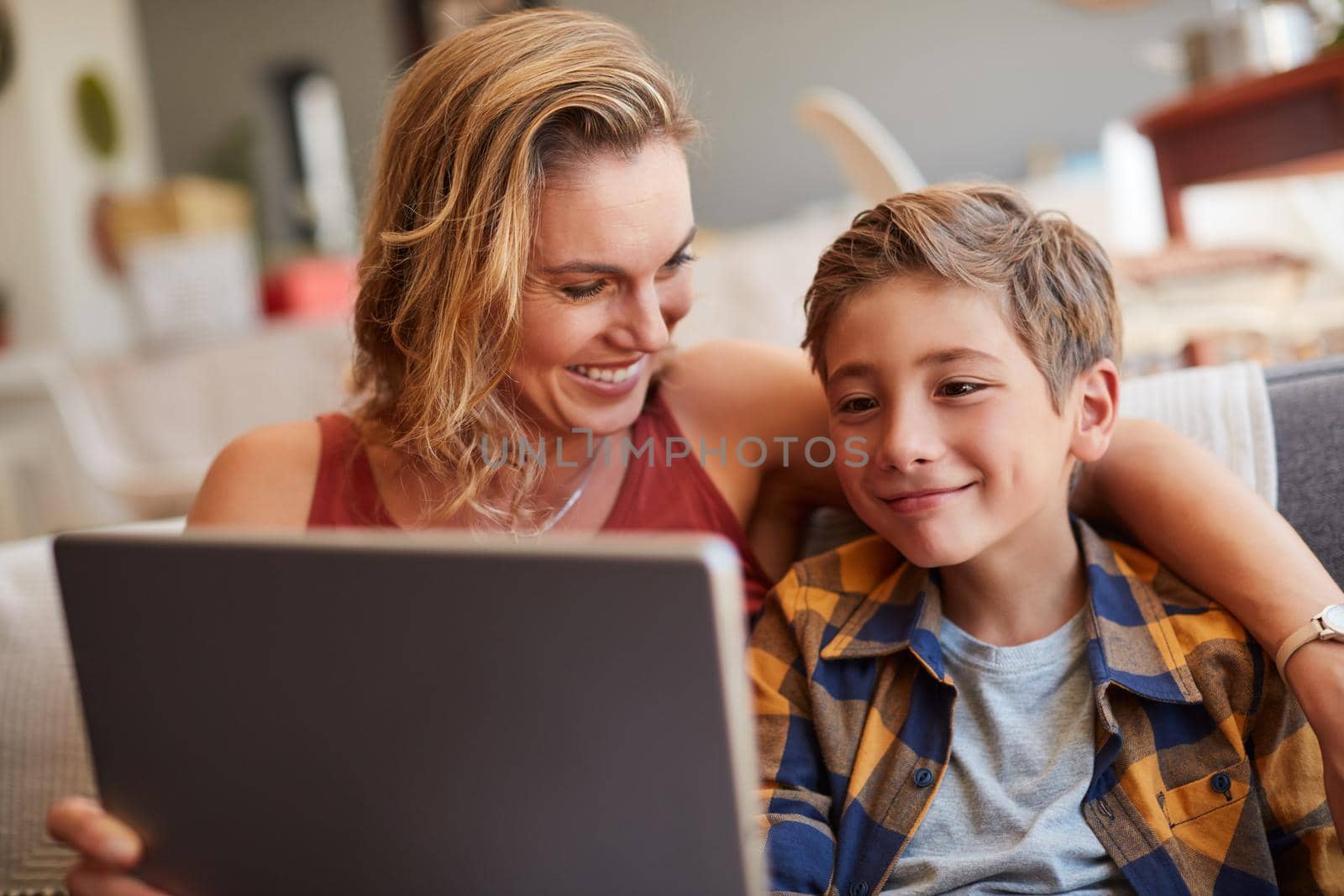 Chill time with their favourite movie. an adorable little boy using a digital tablet with his mother on the sofa at home