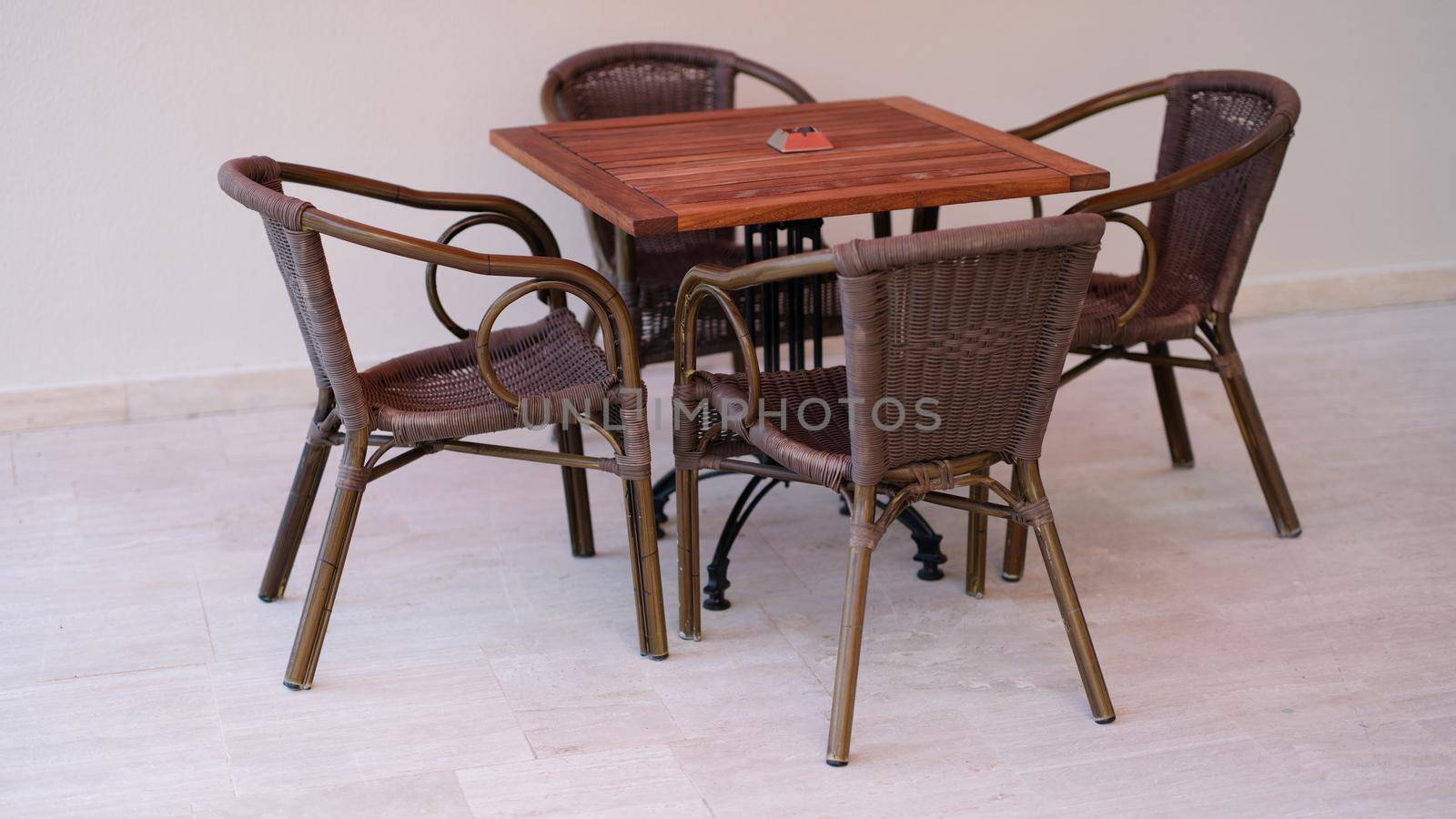 Wicker chairs and wooden table outside closeup. Outdoor summer furniture concept