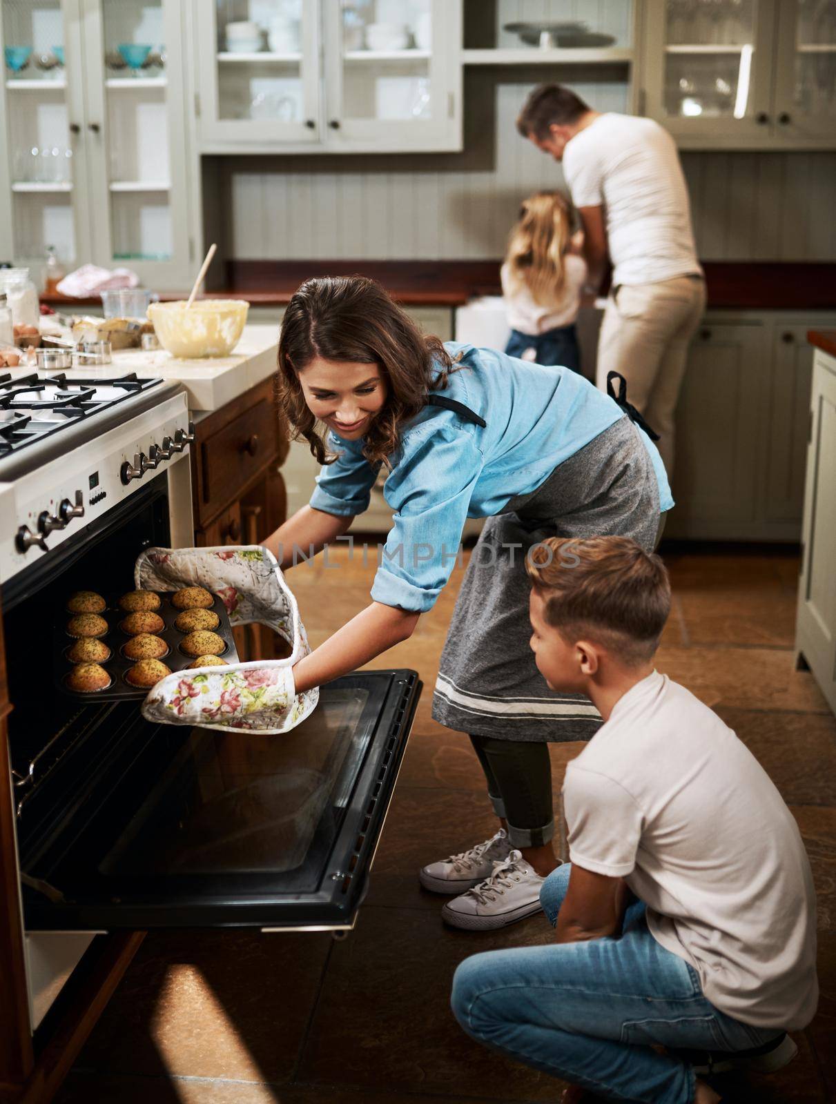 The wait is finally over. a young woman and her son baking muffins in the kitchen at home. by YuriArcurs