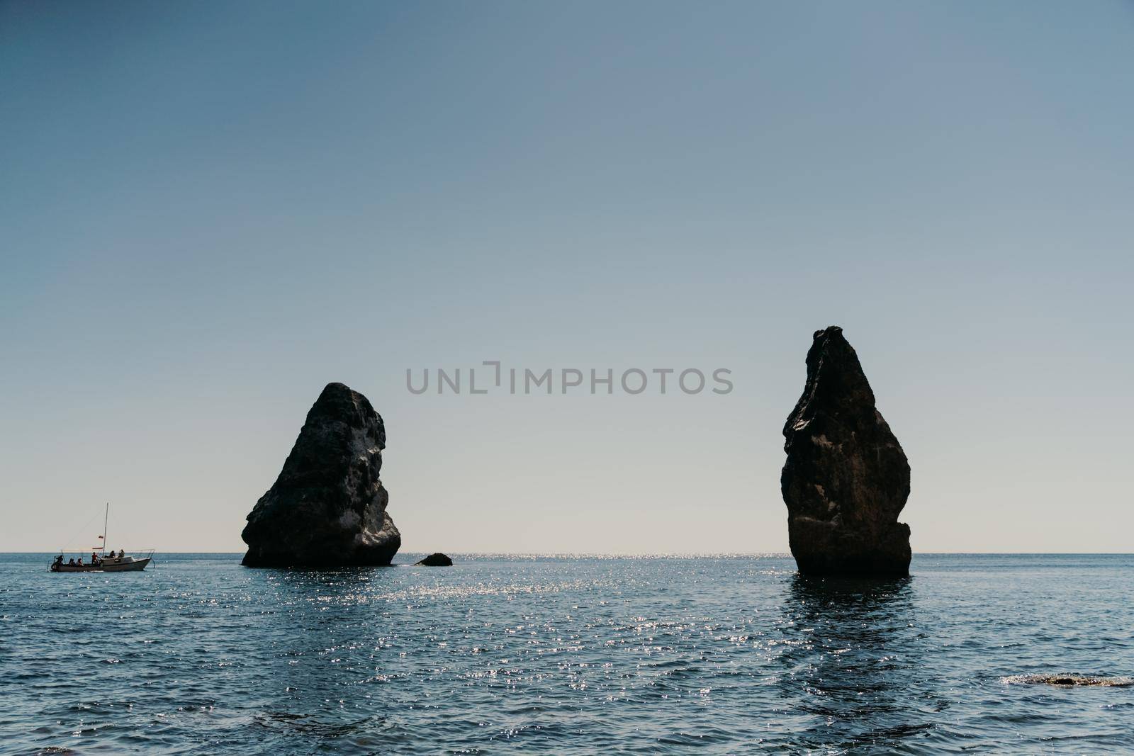 Two rocks stick out of the water in the middle of the turquoise sea. Scenic ocean views. High quality photo. Like in Iceland.