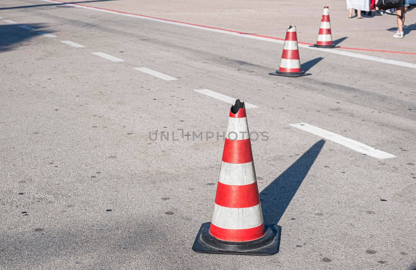 Traffic cone with white and red stripes on the road of the airport. Safety cone.