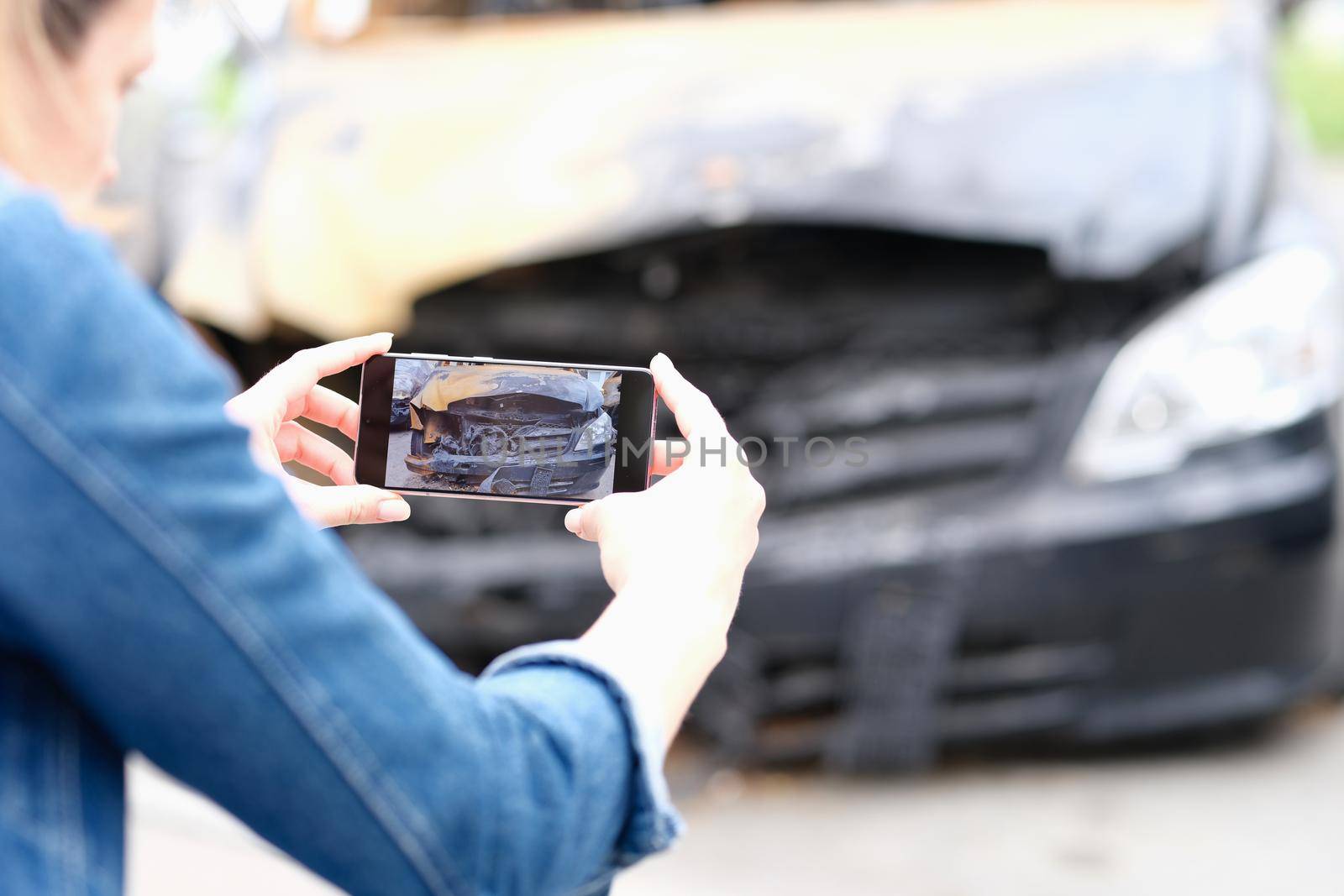 Person photographs burnt car on smartphone closeup by kuprevich