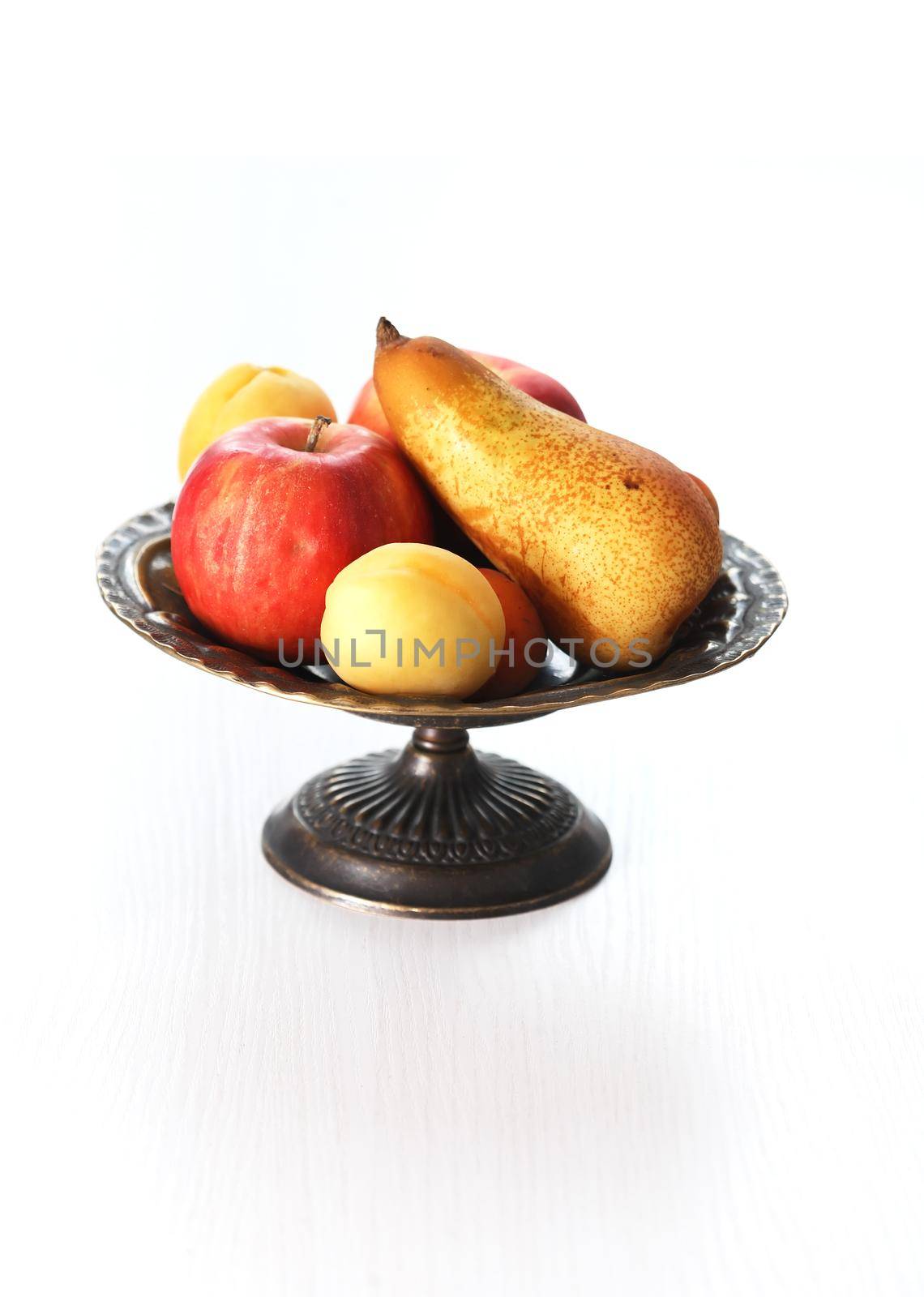 Heap of freshness fruits in vintage bowl on white table