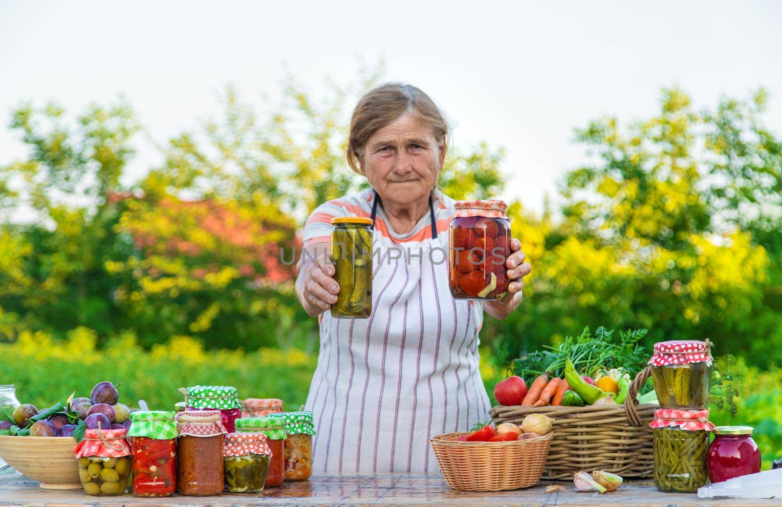 Senior woman preserving vegetables in jars. Selective focus. Food.