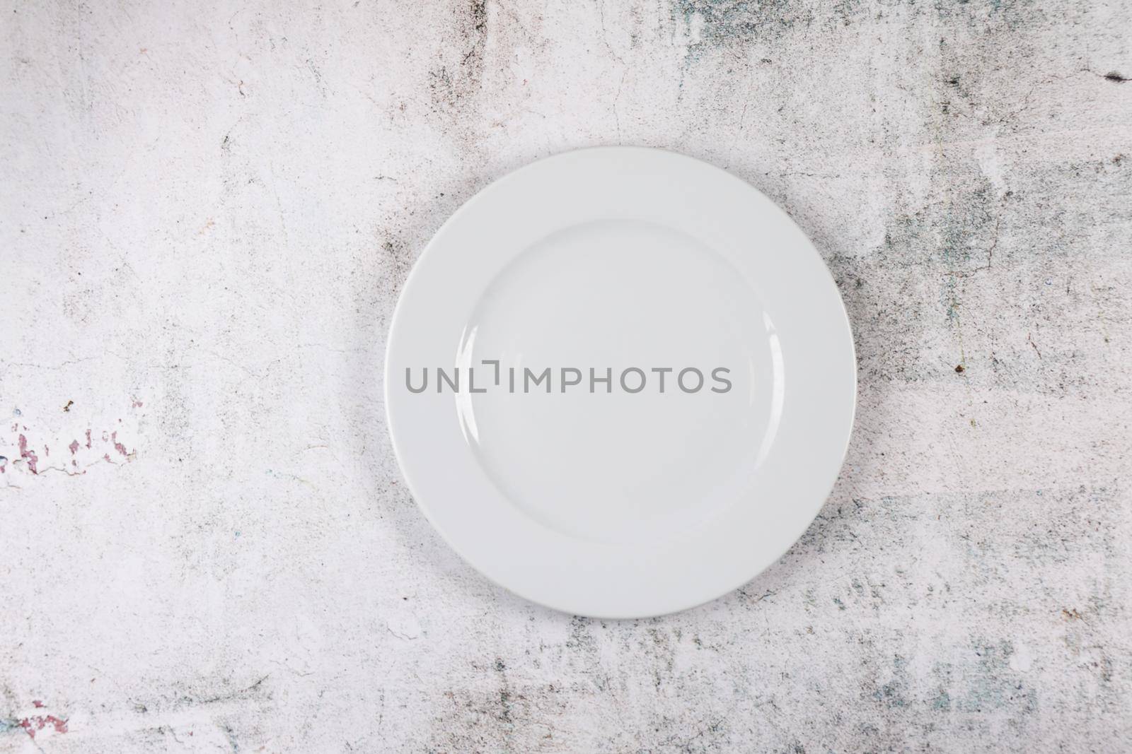 A grey stone surface with white dinner plate place setting