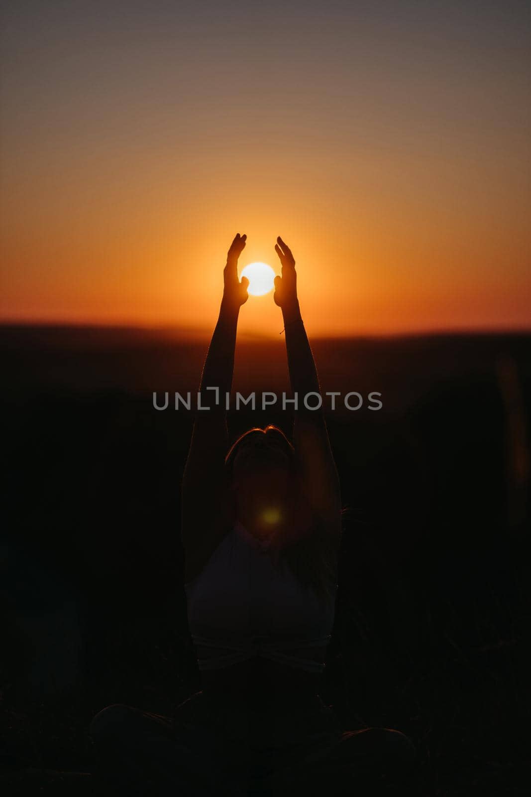 Silhouette Unrecognisable Woman Catching the Sun That Going Under Horizon by Hands at Sunset by Romvy