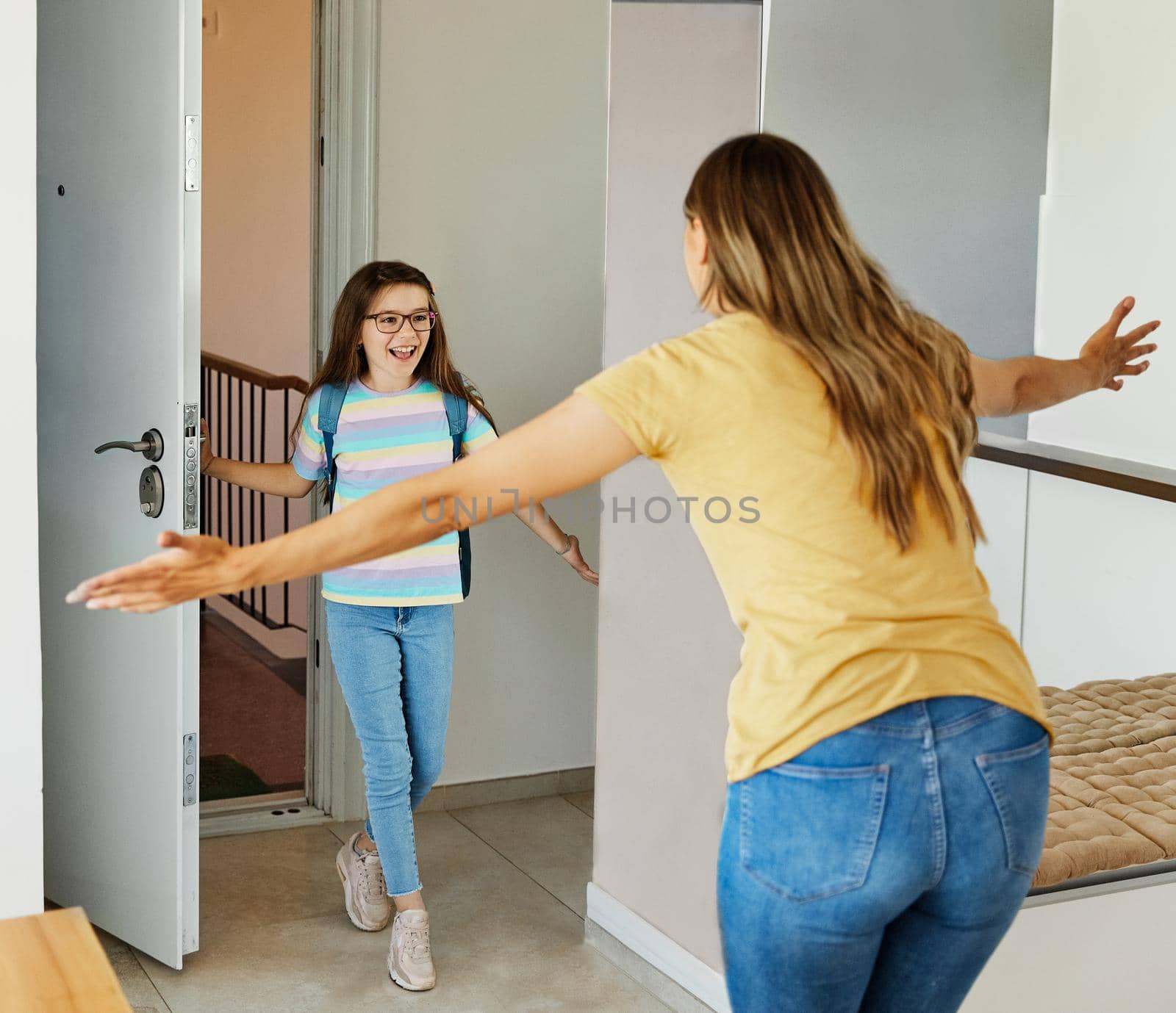 Portriat of a young teen school girl with backpack welcomed by her mother after coming back from school at home