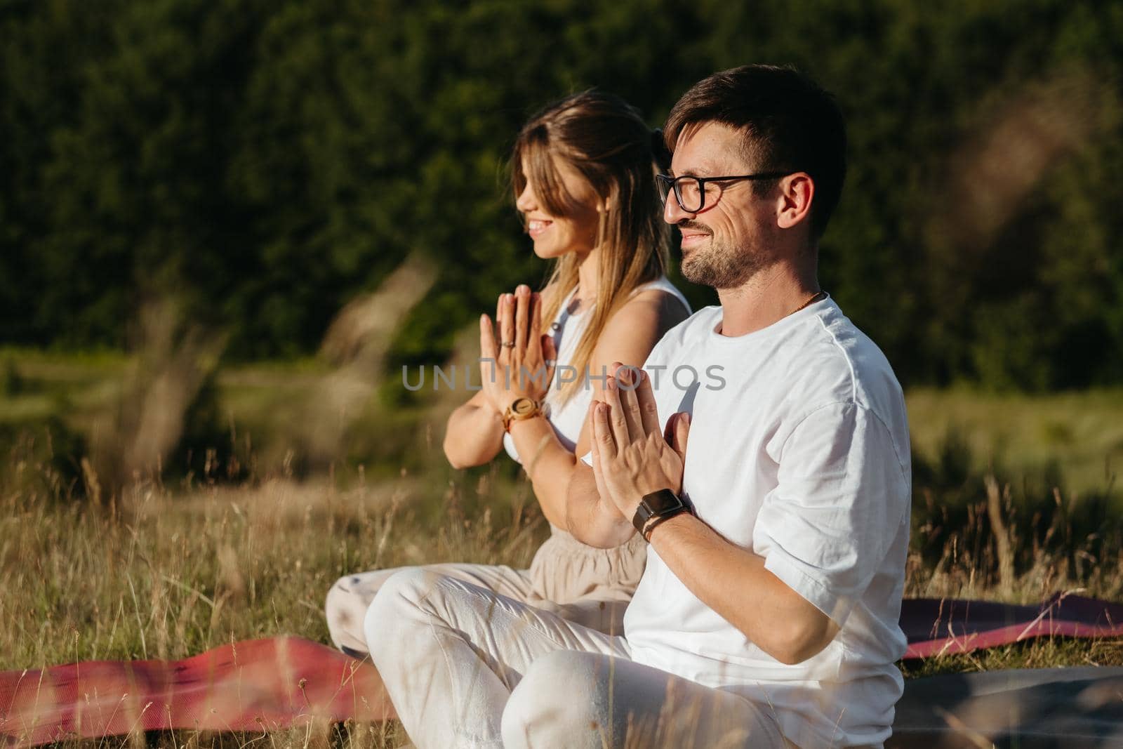 Young Adult Couple Meditating Outdoors in the Nature, Cheerful Woman and Happy Man Practicing Yoga by Romvy