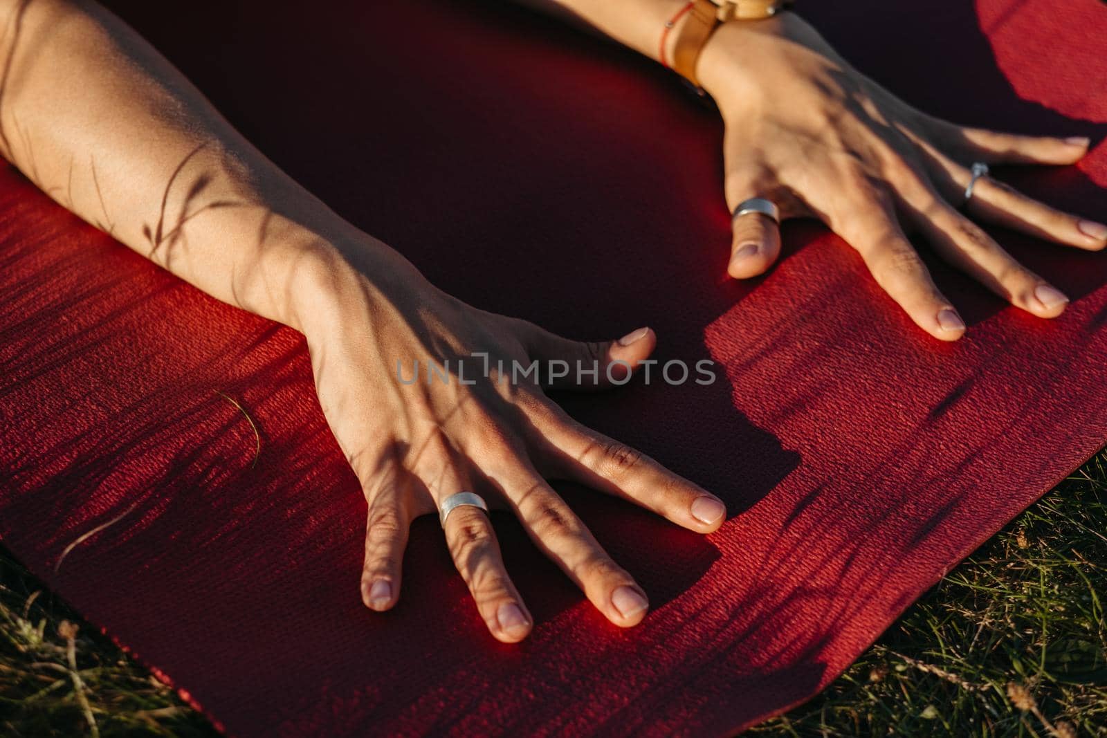 Close Up Unrecognisable Woman Holding Her Hands on the Mat During Yoga Outdoors at Sunset by Romvy