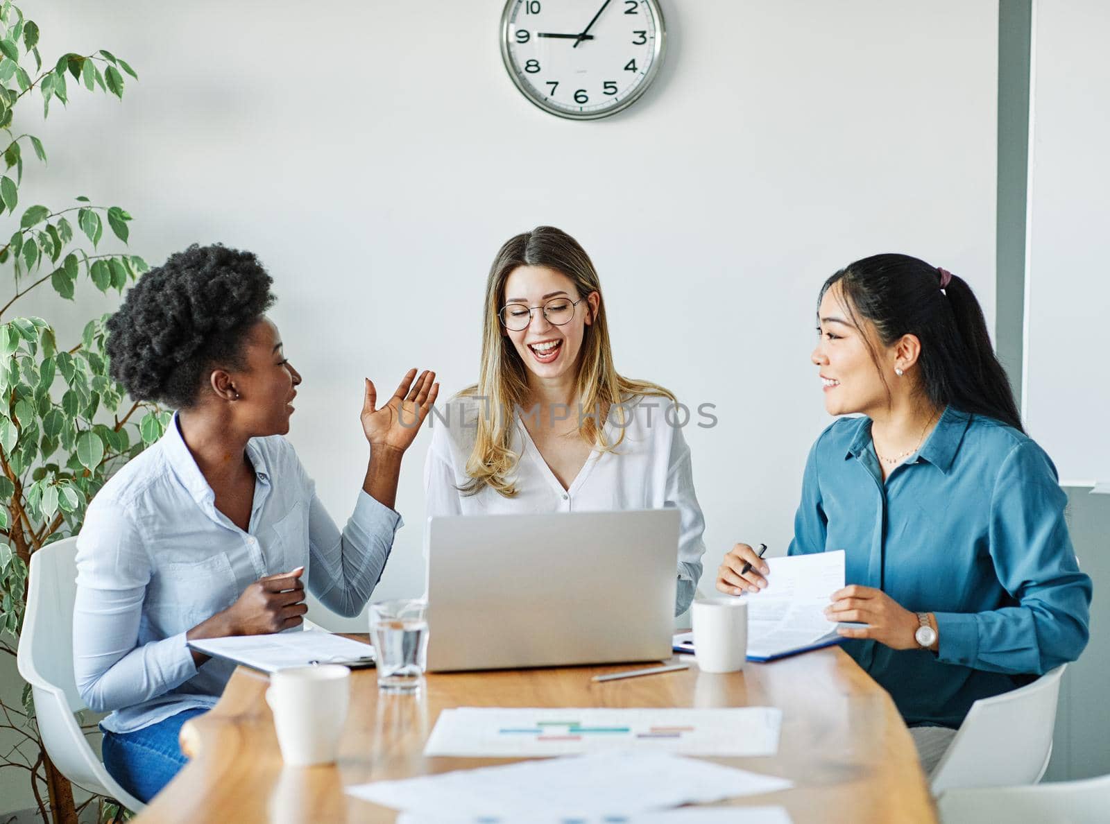 Portrait of a group of young businesswomen multiethnic working with laptop on desk and talking in a start up office