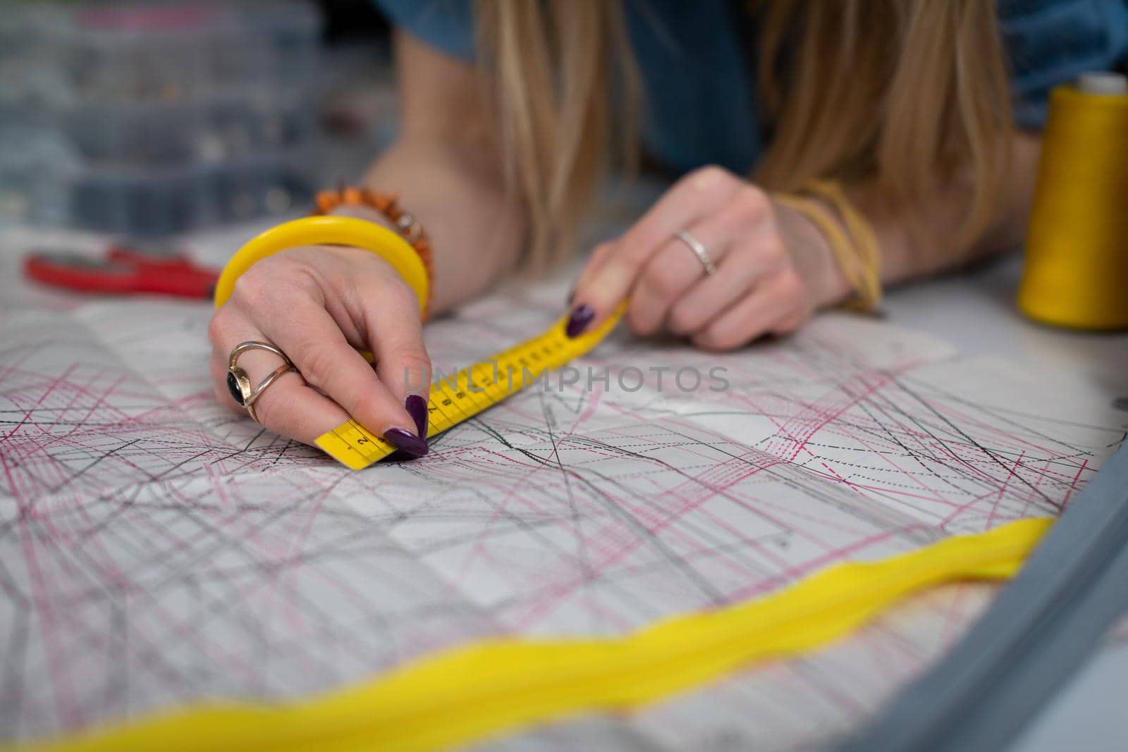 Measuring directly on a paper drawing of blanks with different sizes of garments. Tailor's workshop up close.