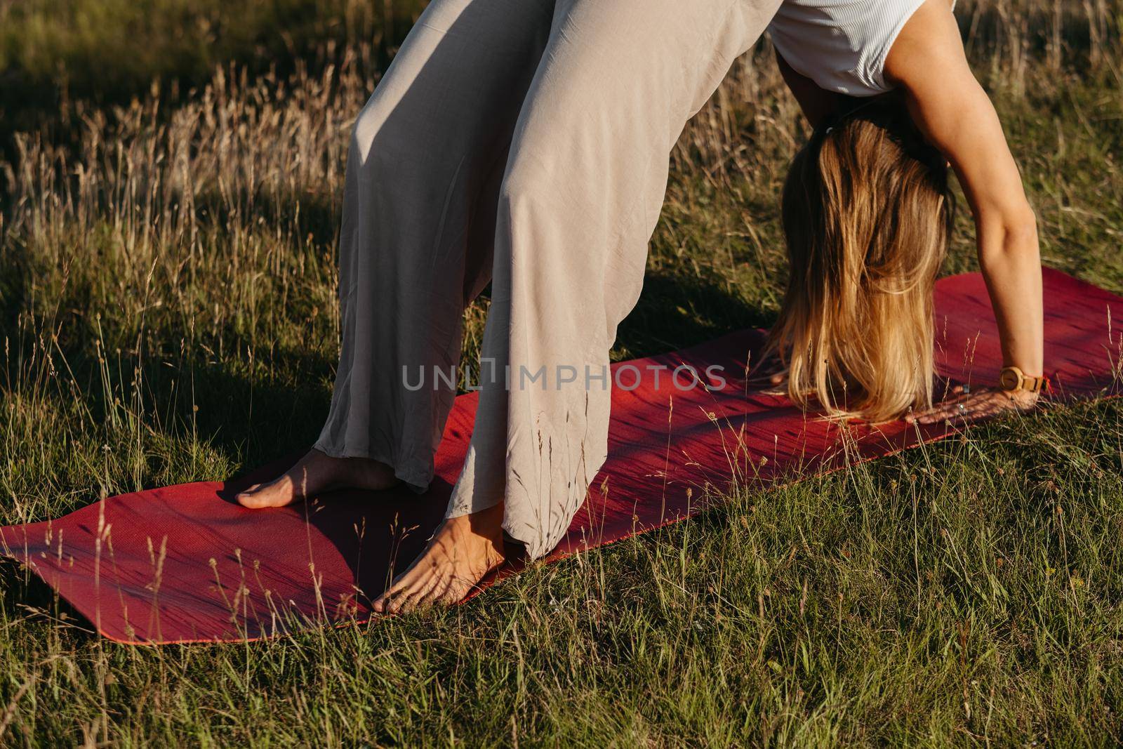 Close Up Unrecognisable Woman Doing Bridge Exercise on the Mat During Yoga Practice Outdoors with Beautiful Background by Romvy