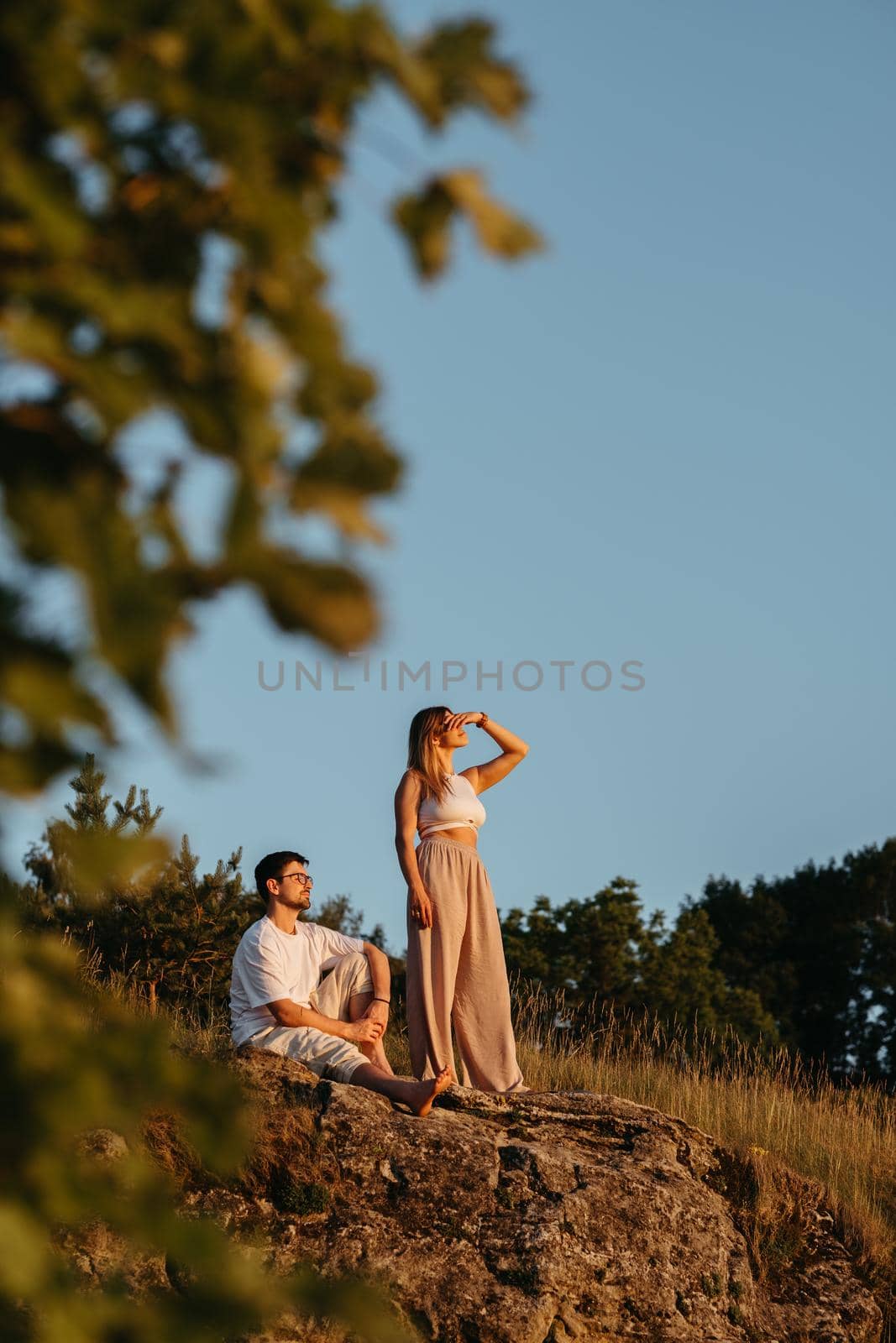 Young Adult Couple, Man and Woman Enjoying Beautiful Sunset Outdoors in the Nature by Romvy