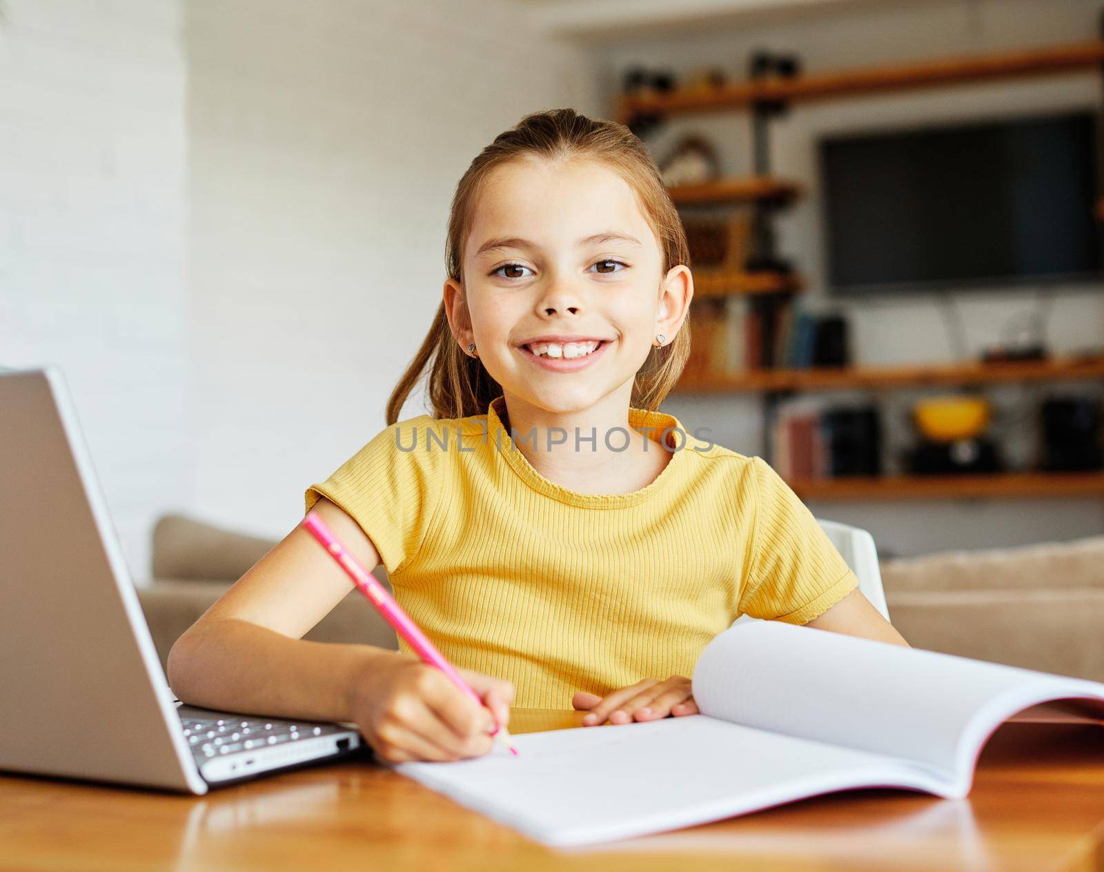 Portrait of a little girl having fun using laptop or doing homework with laptop at home