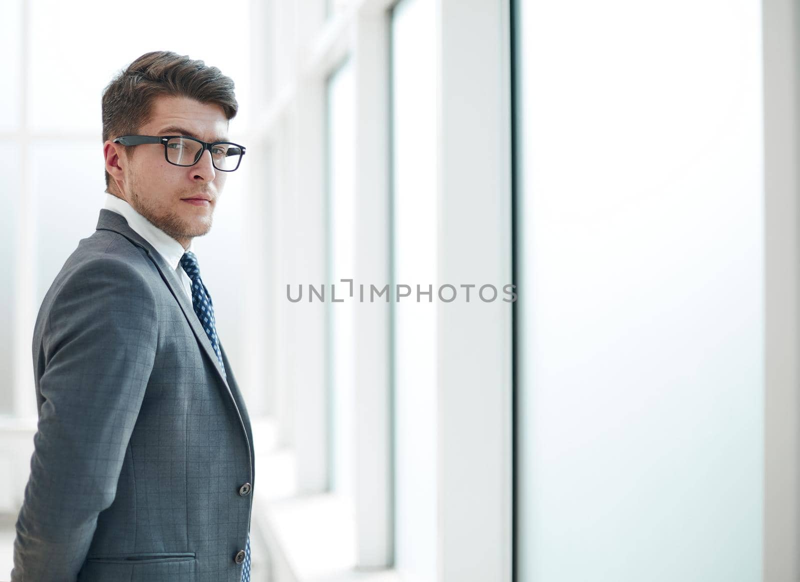 Portrait of a young businessman wearing glasses and standing in office