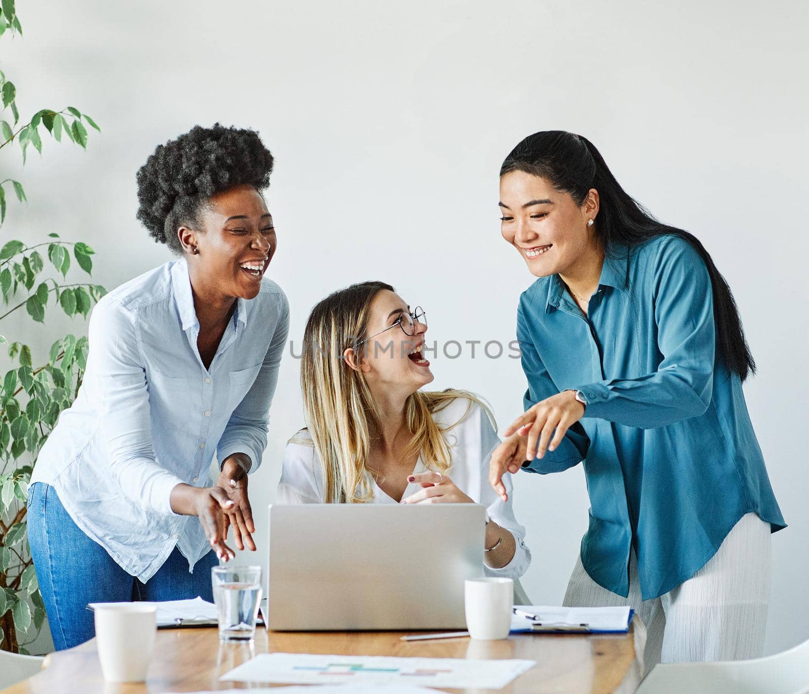 Portrait of a group of young businesswomen multiethnic working with laptop on desk and talking in a start up office