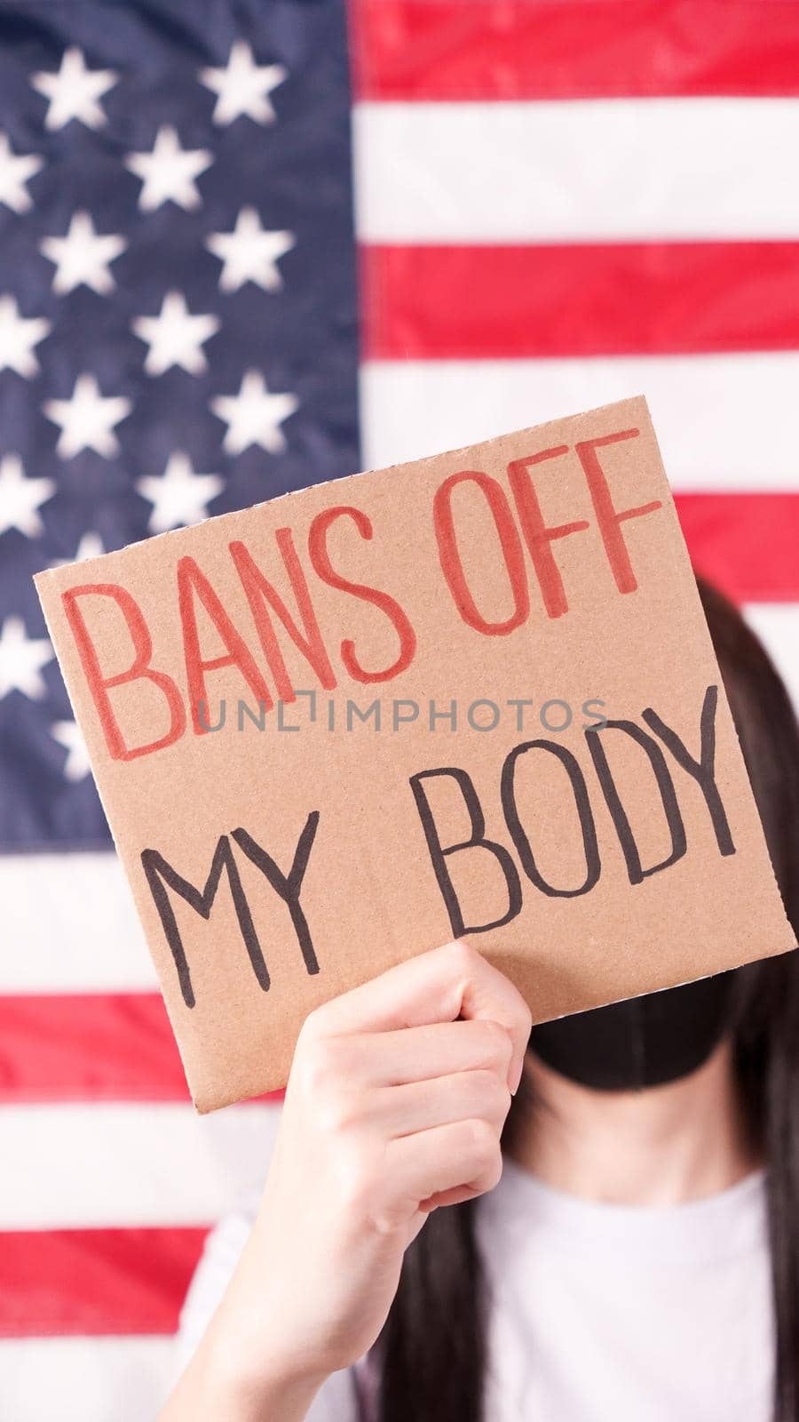 Young woman holding sign Bans Of My Body covering face stop abortion American flag on background. Anti domestic violence, racism racial discrimination. Struggle for women rights, social problems. by JuliaDorian