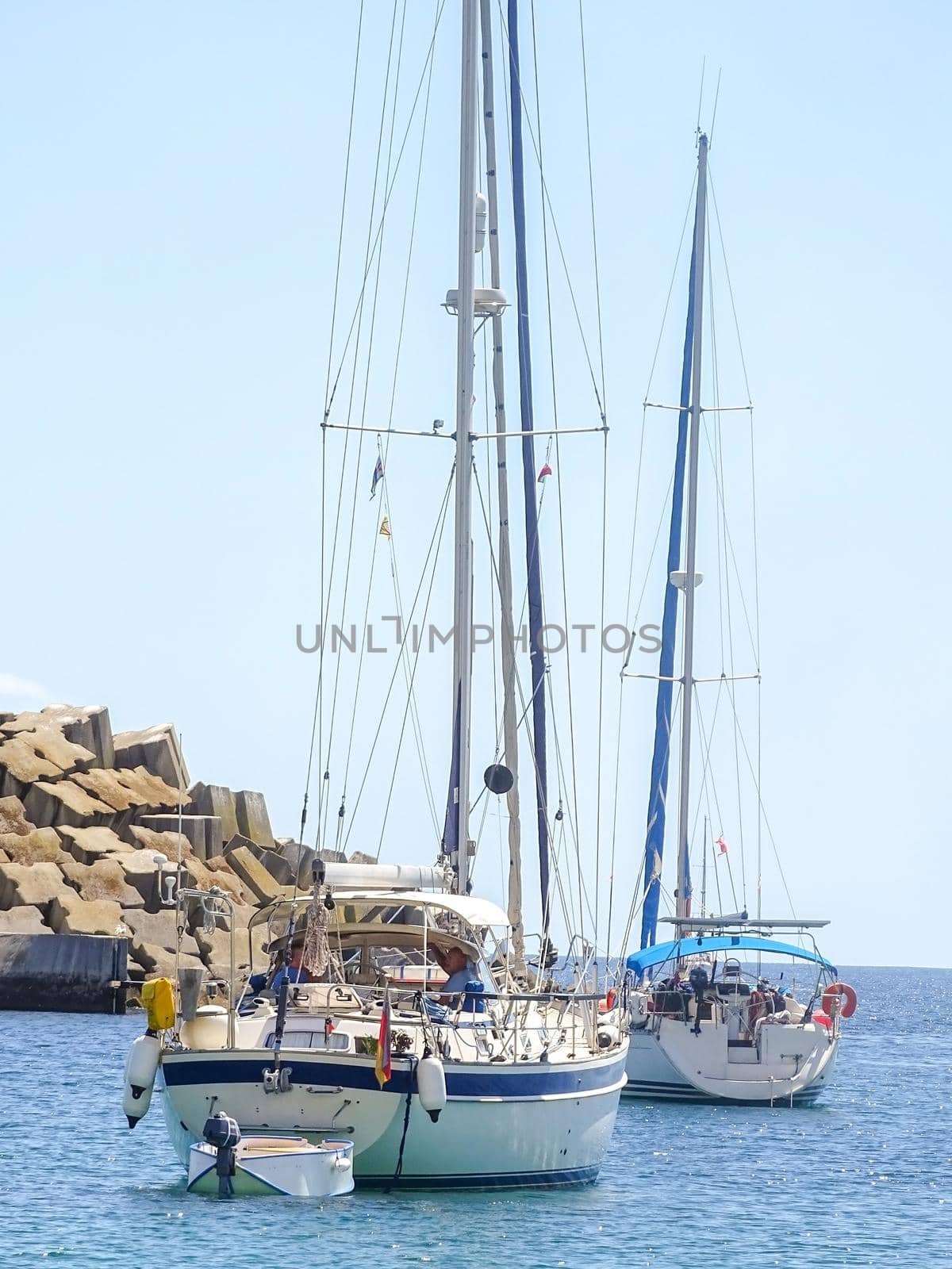 Two white yachts in the bay with lowered sails on a sunny day