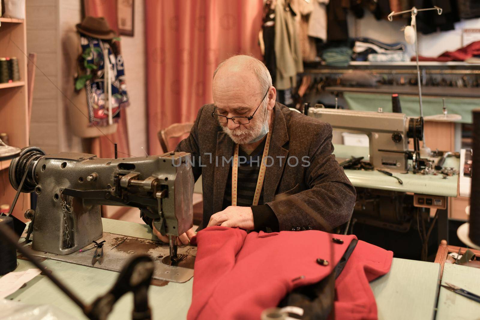 A gray-haired man works at a sewing machine