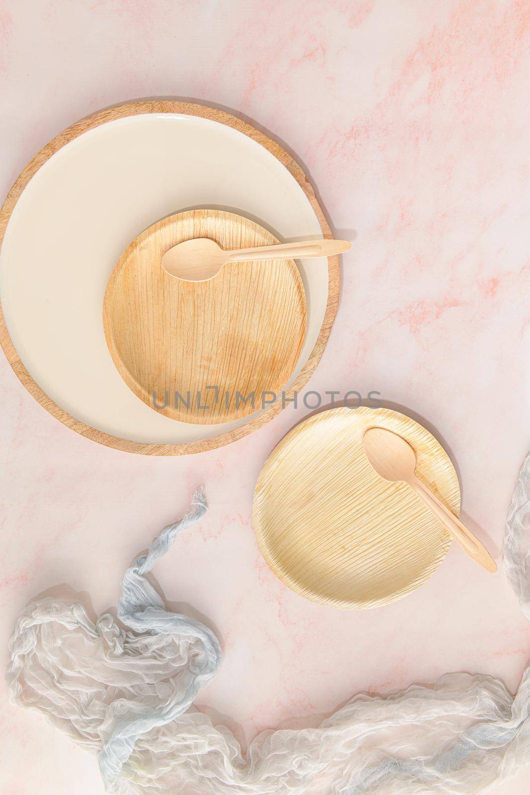 Areca leaf plates with recyclable spoons on a pink marble kitchen counter. Healthy food concept with environmental sustainability concerns.